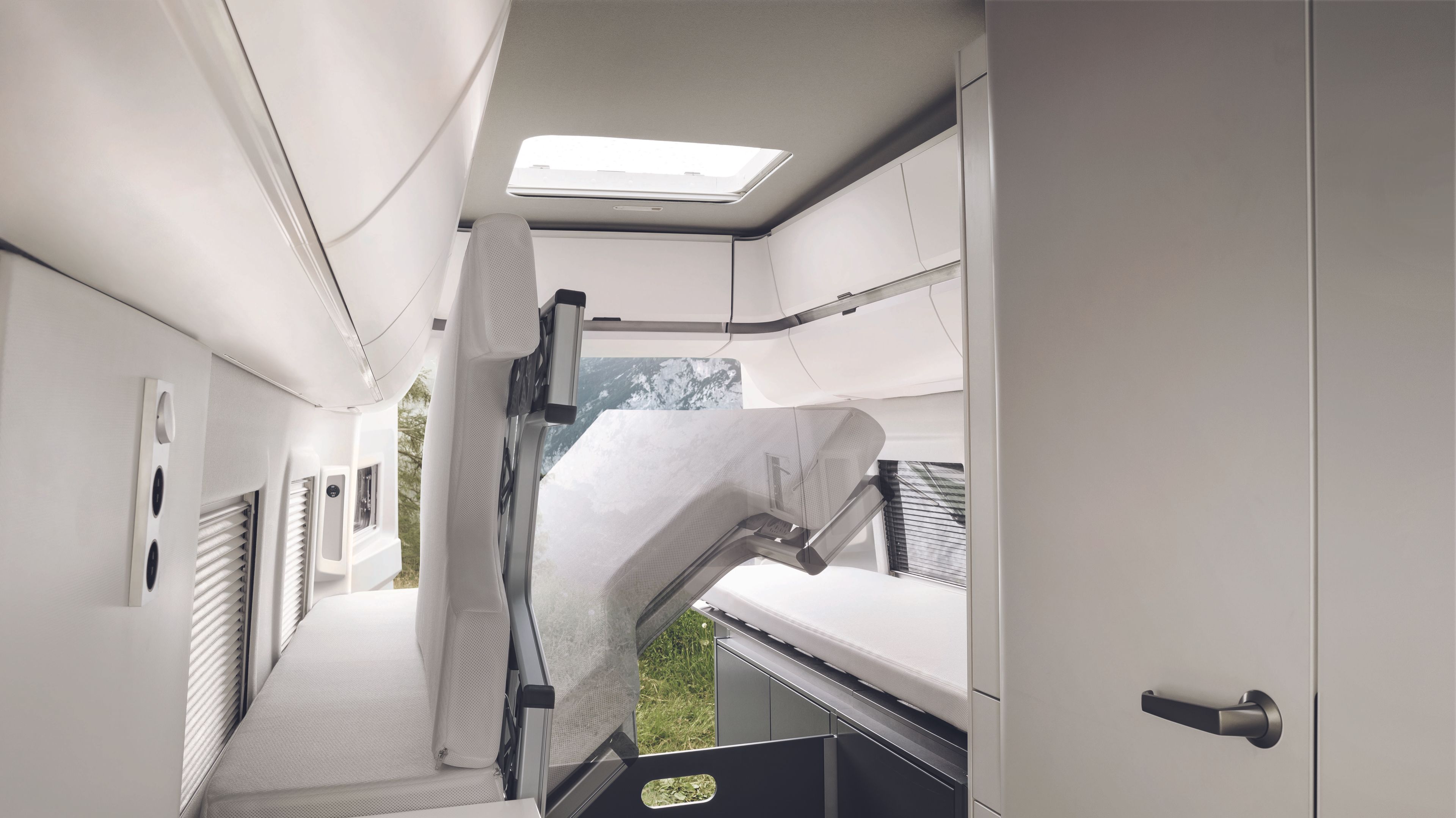 Vista da traseira da autocaravana VW Grand California 680. A cama longitudinal está rebatida para cima. Por baixo dela, vê-se o espaço de arrumação infeiror.