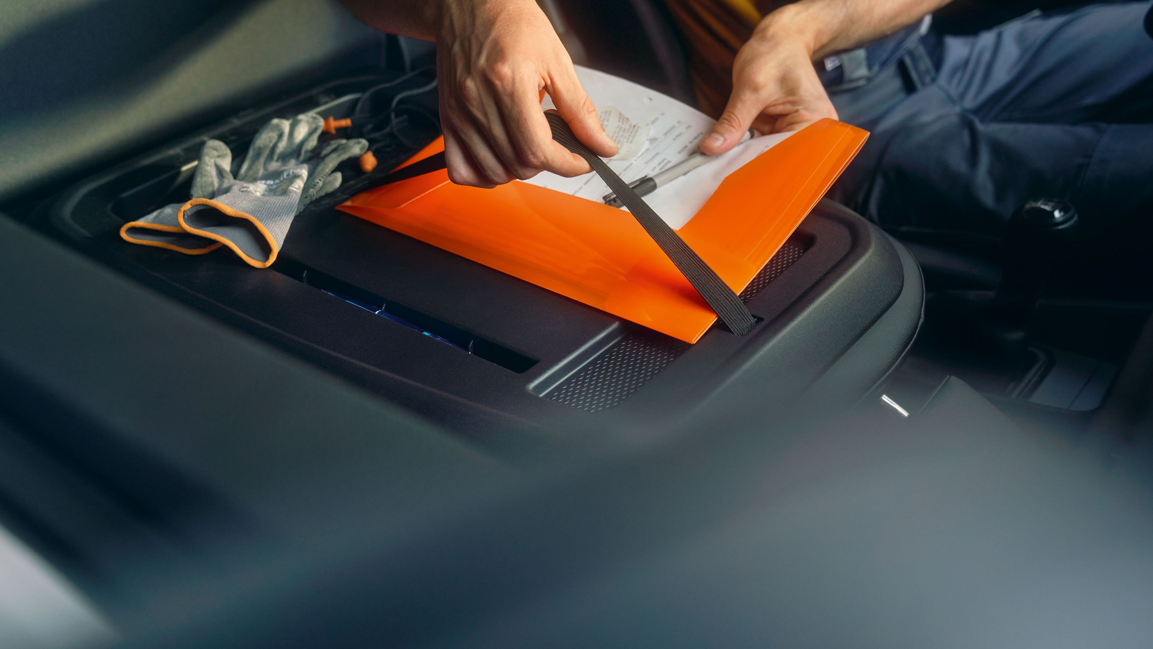 Um homem fixa uma pasta na parte de trás do banco do passageiro da nova carrinha Volkswagen Caddy Cargo.