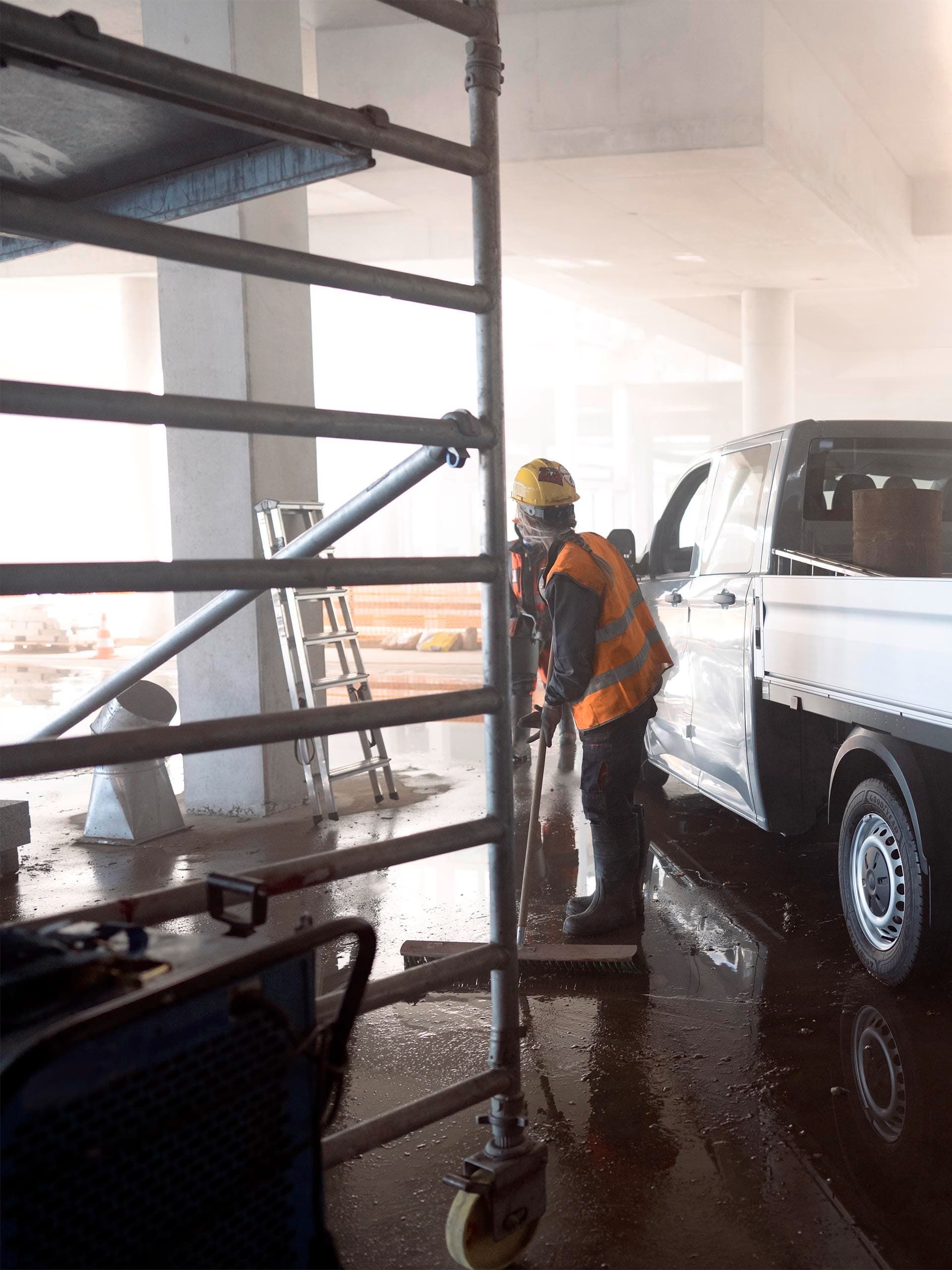 Vários trabalhadores da construção civil a fazer uma pausa à volta de um Volkswagen Crafter com plataforma de carga.