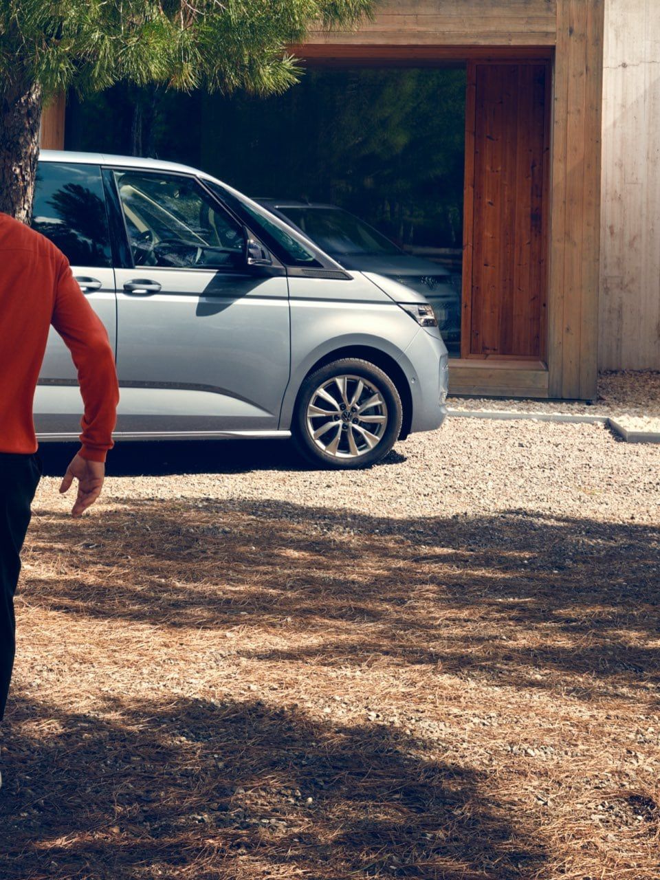 Dois homens correm para uma VW Multivan Life estacionado.