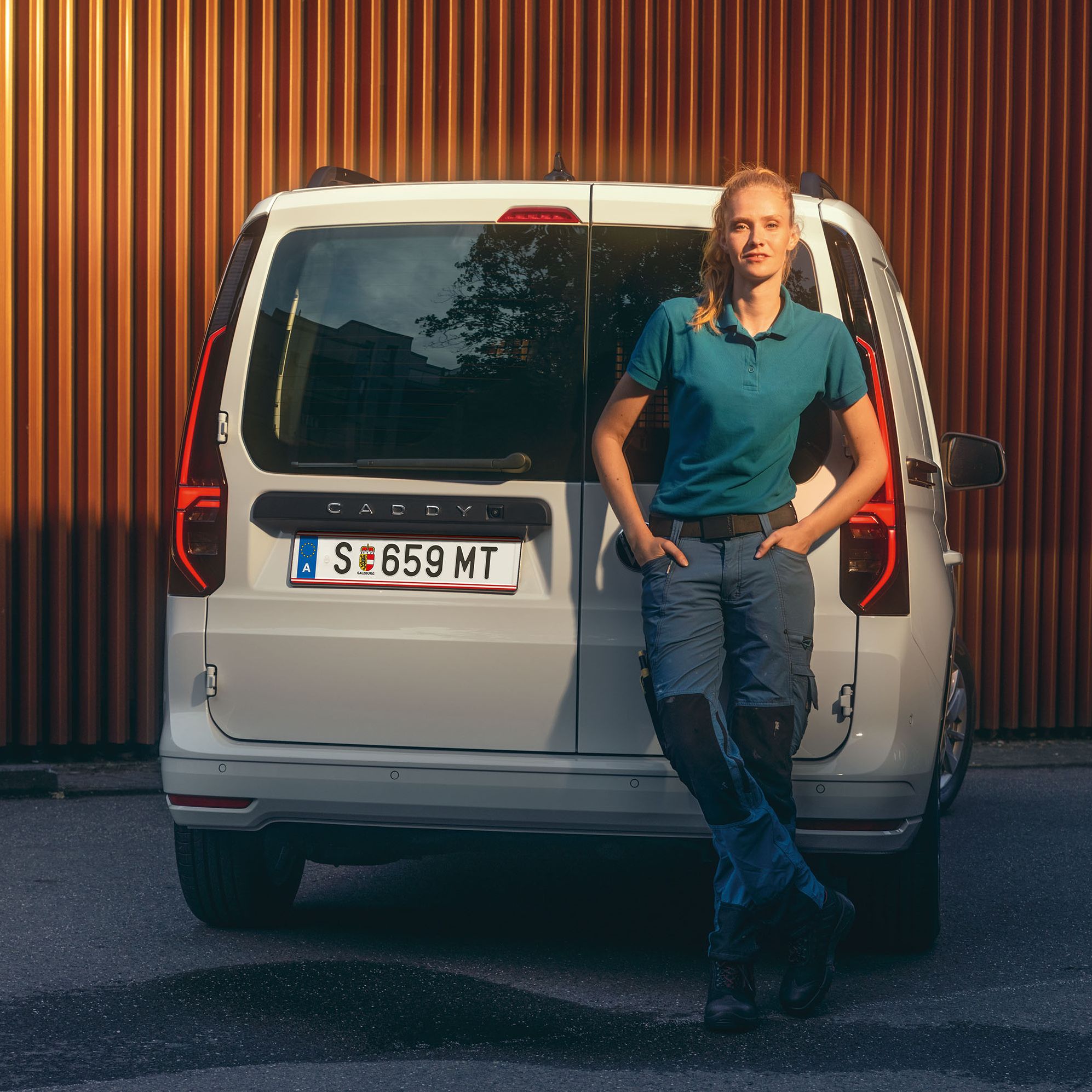 Uma mulher enconstada à traseira do novo furgão VW Caddy Cargo