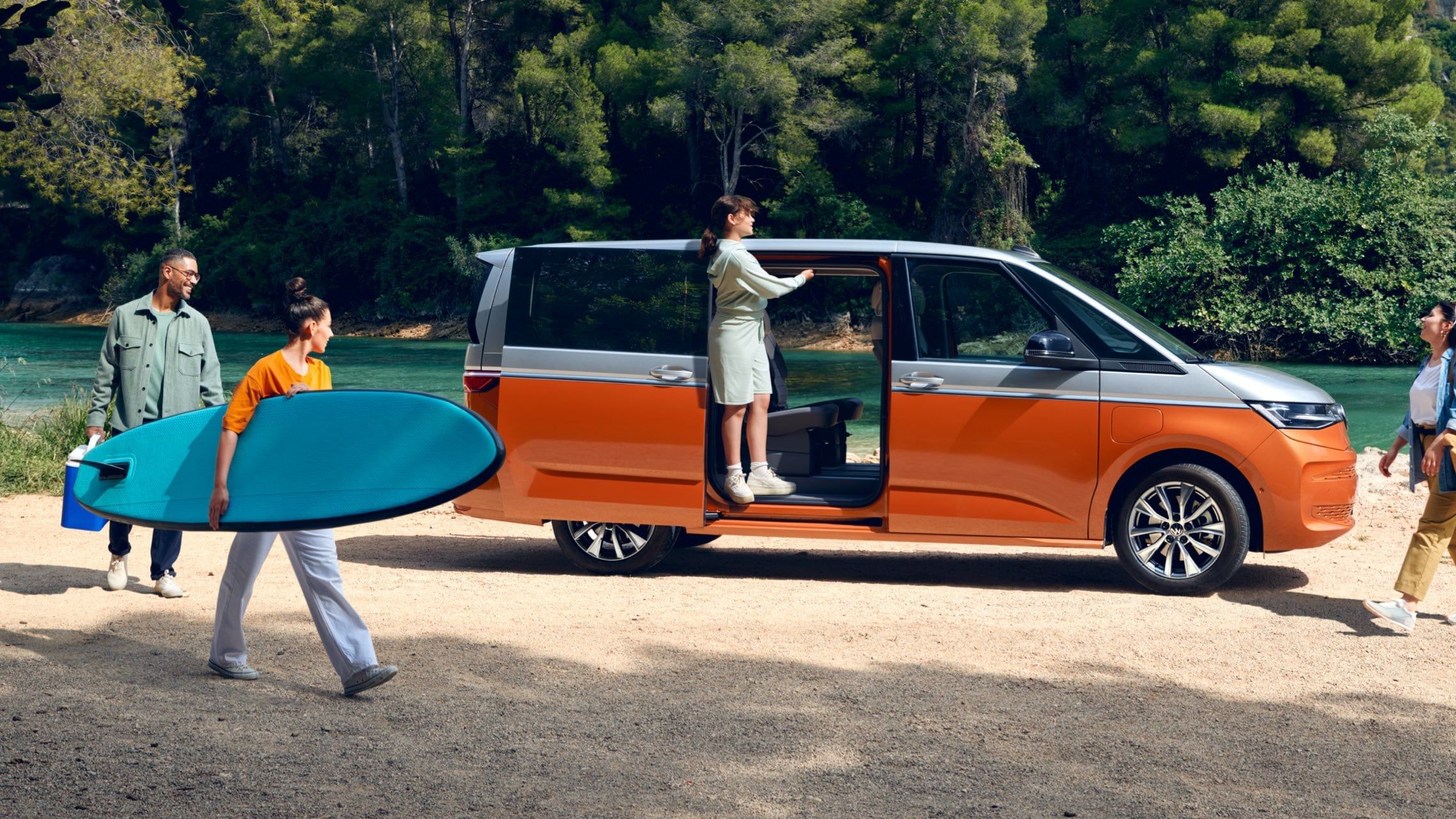 Uma família estaciona o seu VW Multivan Energetic numa praia fluvial.