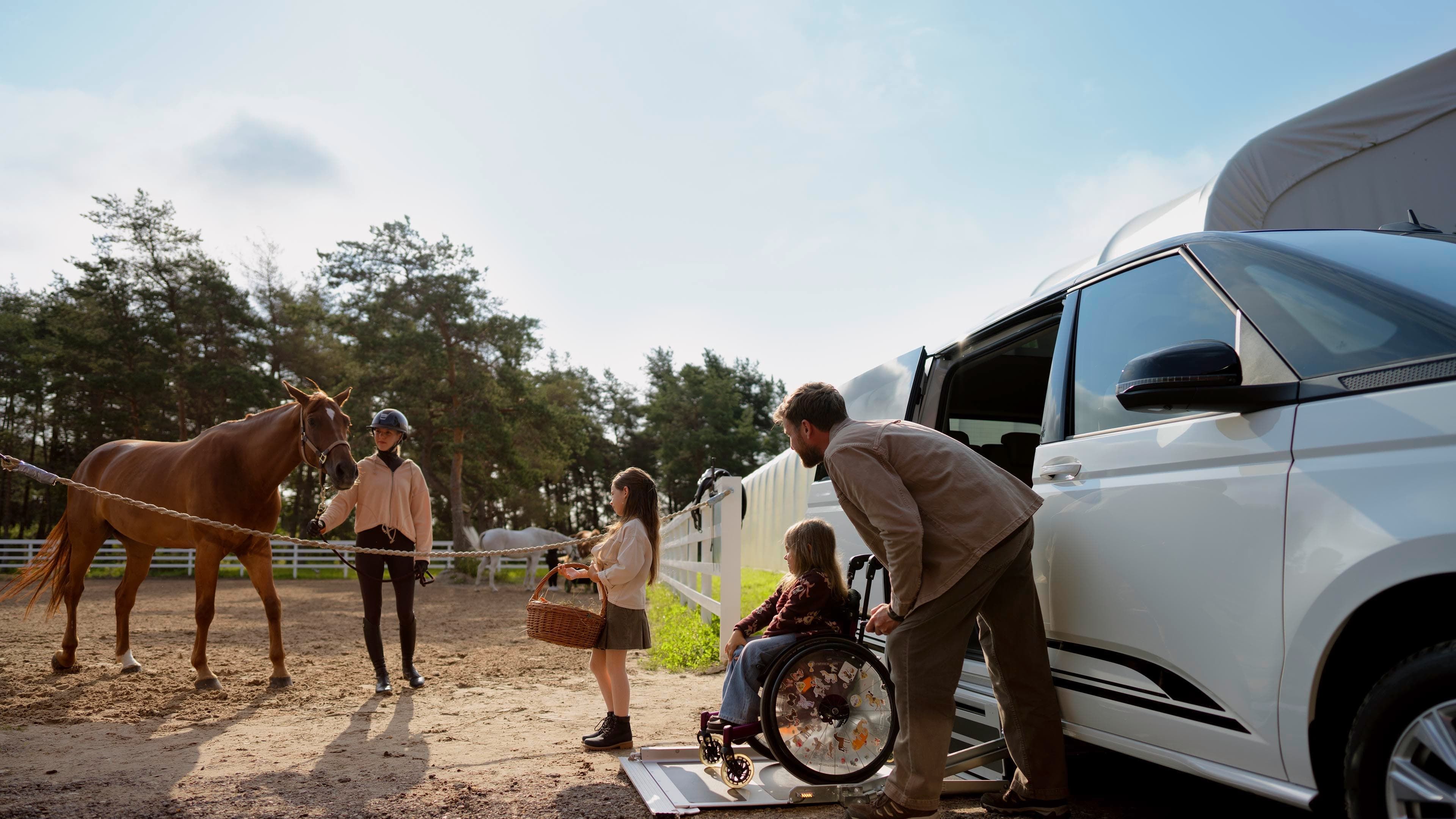 Uma criança em cadeira de rodas sai de um Volkswagen Caddy com rampa para cadeiras de rodas. 