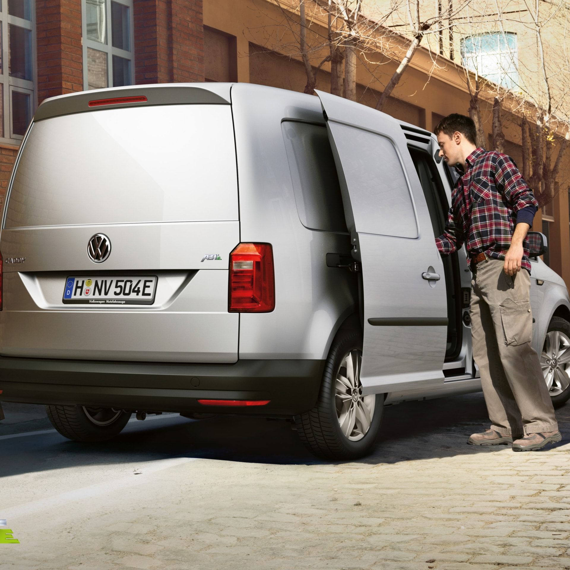 Empregado de serviços VW verifica uma lista de verificação de serviços em frente a um VW vermelho com capô aberto
