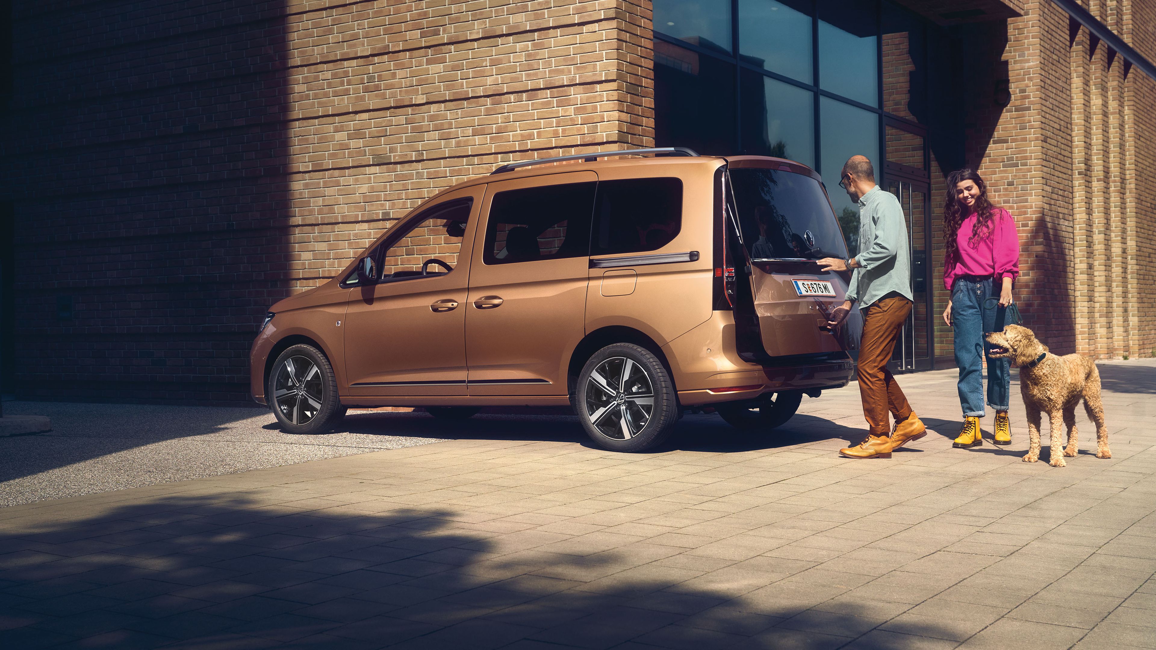 Ein Mann öffnet die Heckklappe mit Fenster eines VW Caddy.