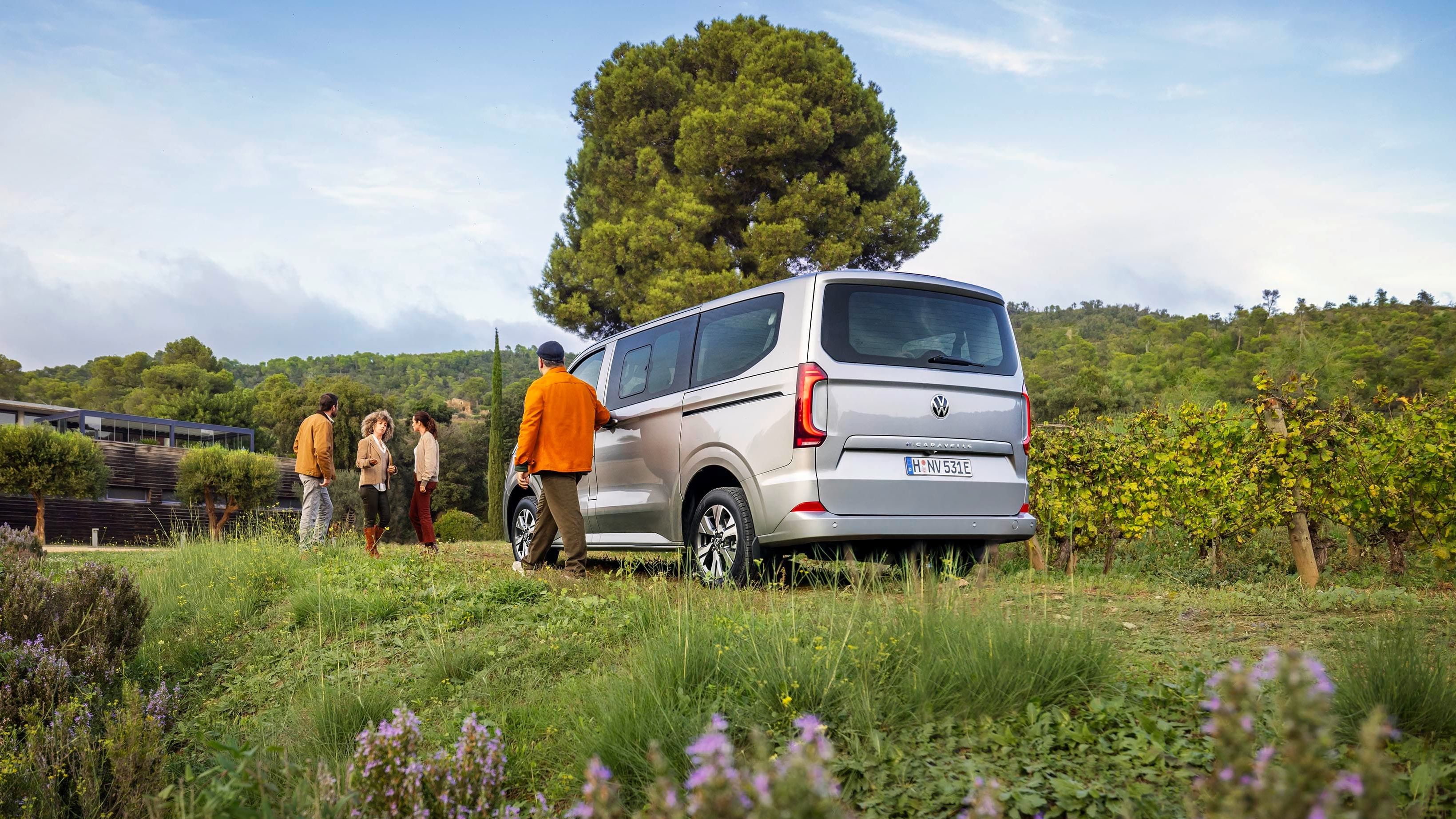 Uma Caravelle estacionada num prado onde amigos se encontram.
