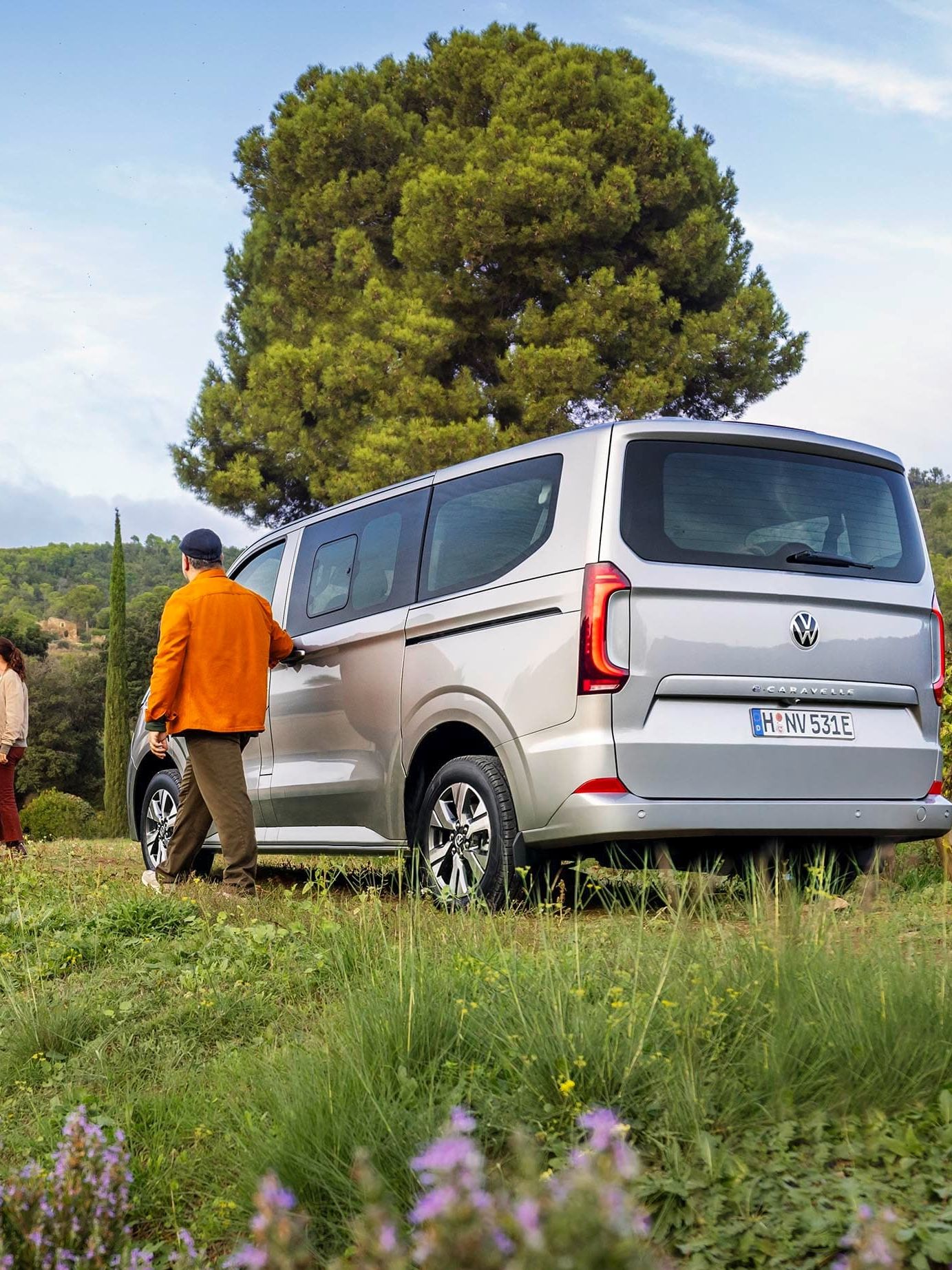 Uma Caravelle estacionada num prado onde amigos se encontram.