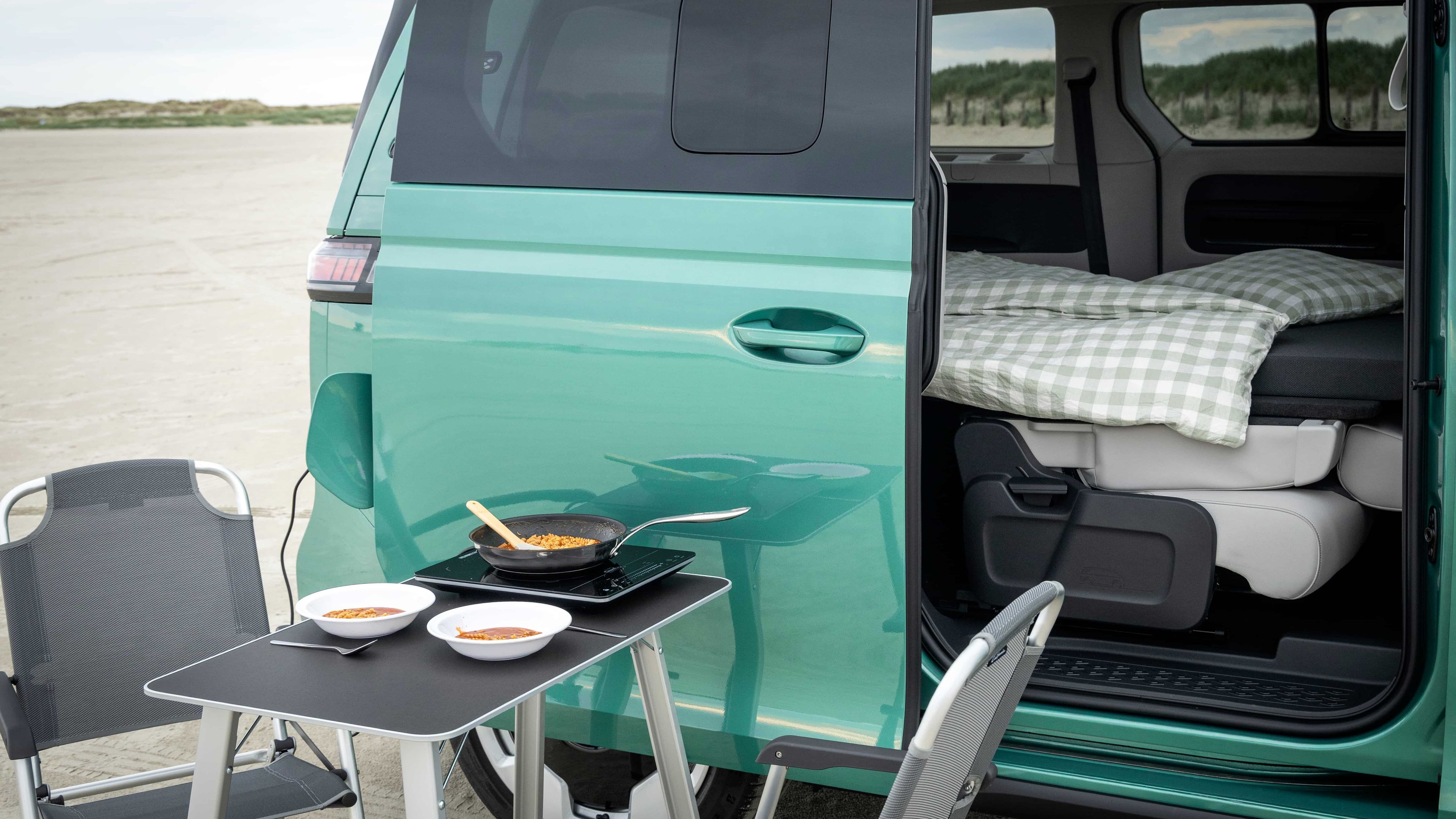 Volkswagen ID. Buzz Pacote Boa Noite vista lateral com uma mesa e duas cadeiras