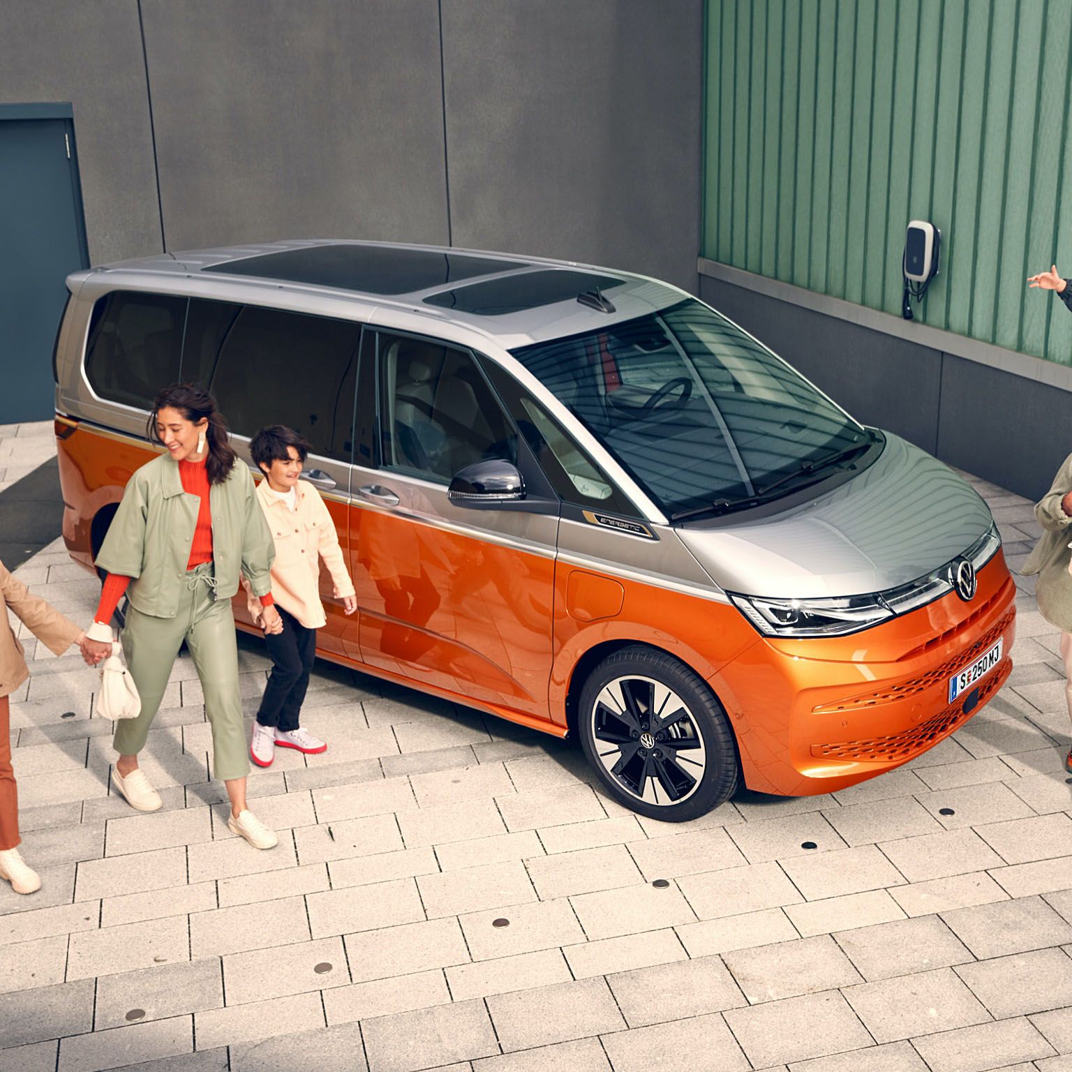 Eine Familie läuft vergnügt neben dem stehenden VW Multivan Energetic T7 2021 her