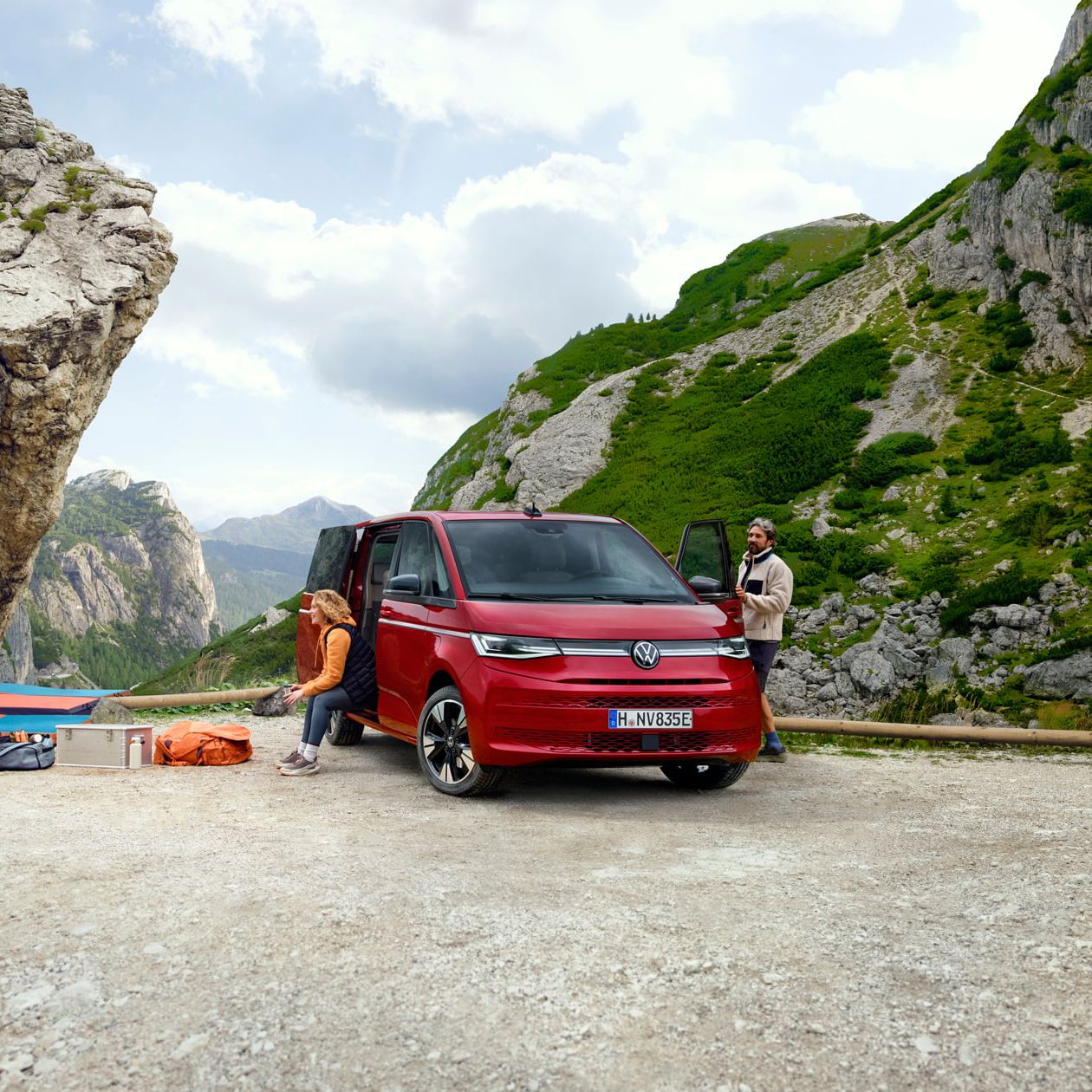 Volkswagen Multivan numa paisagem de montanhas com um grupo de pessoas a escalar.