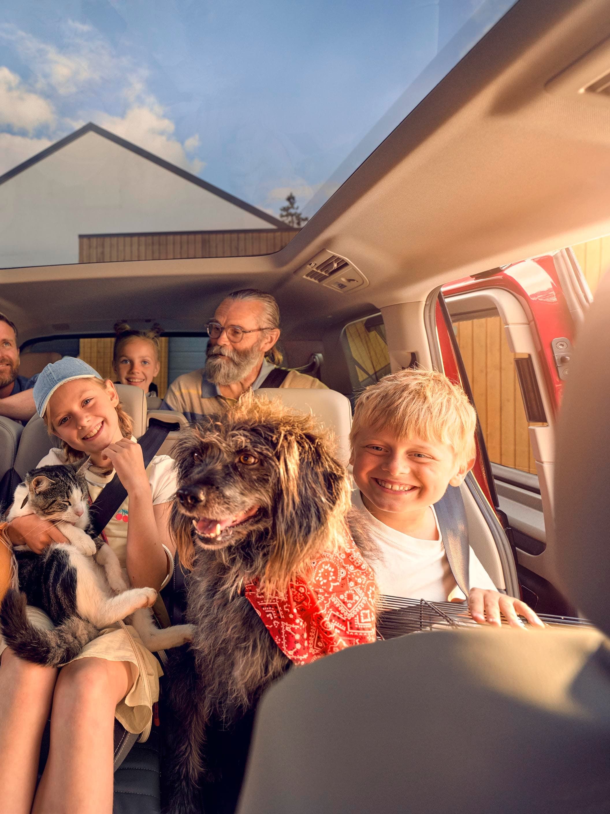 Uma família numerosa com um cão, um gato e um peluche nas duas filas de bancos traseiras de uma Volkswagen Multivan.