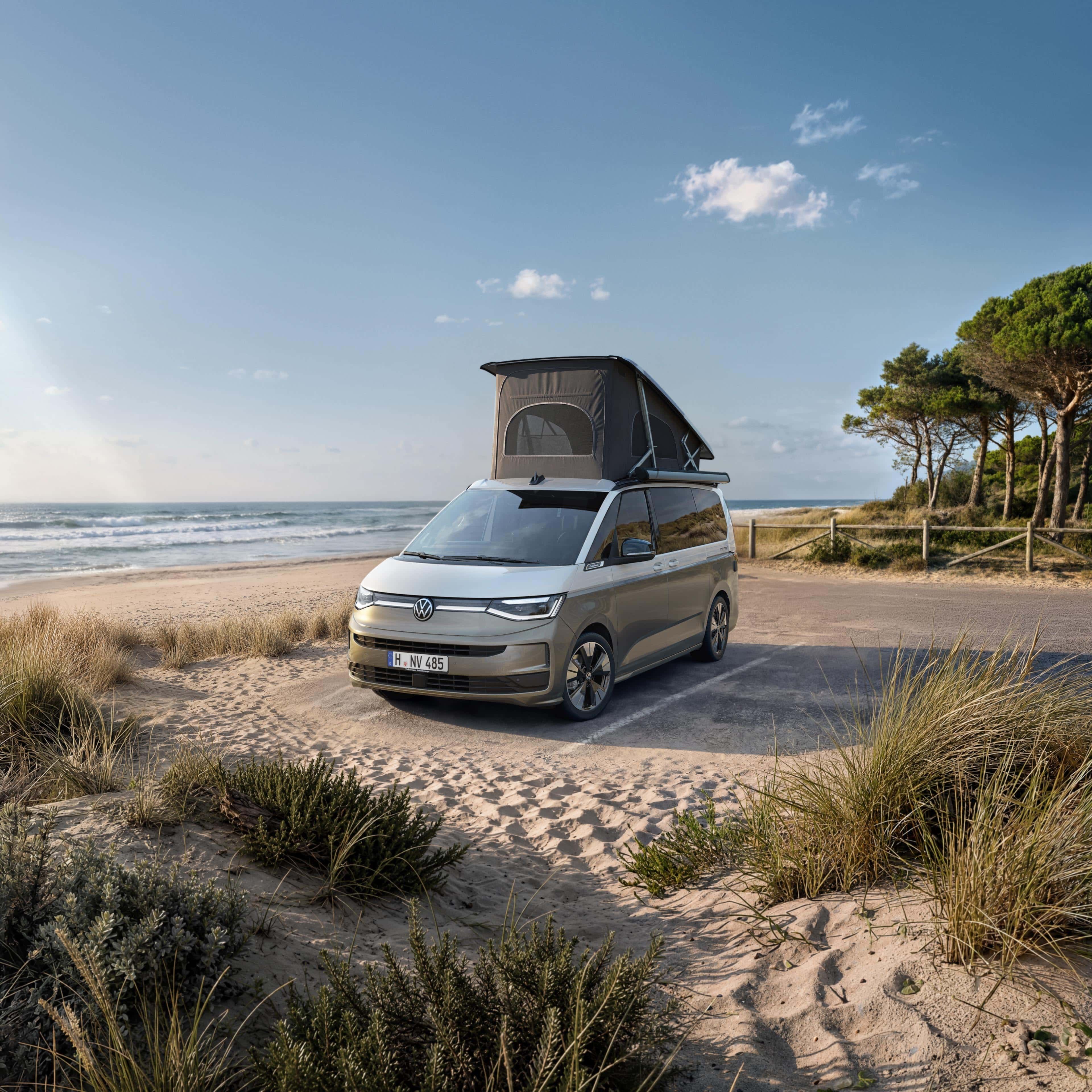 VW California com teto elevatório parada num estacionamento na praia.