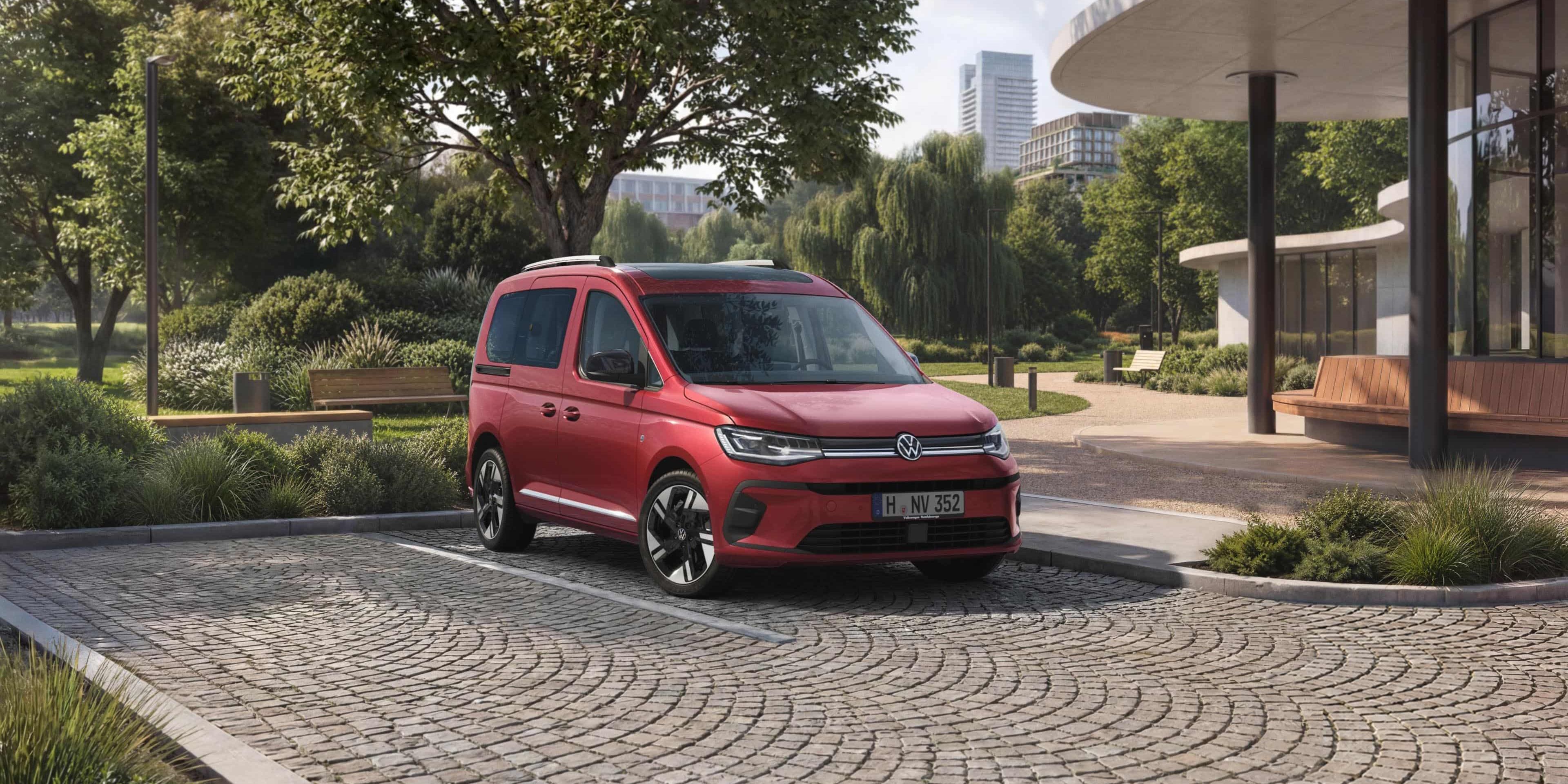 VW Caddy vermelha num estacionamento em frente a um parque numa cidade.