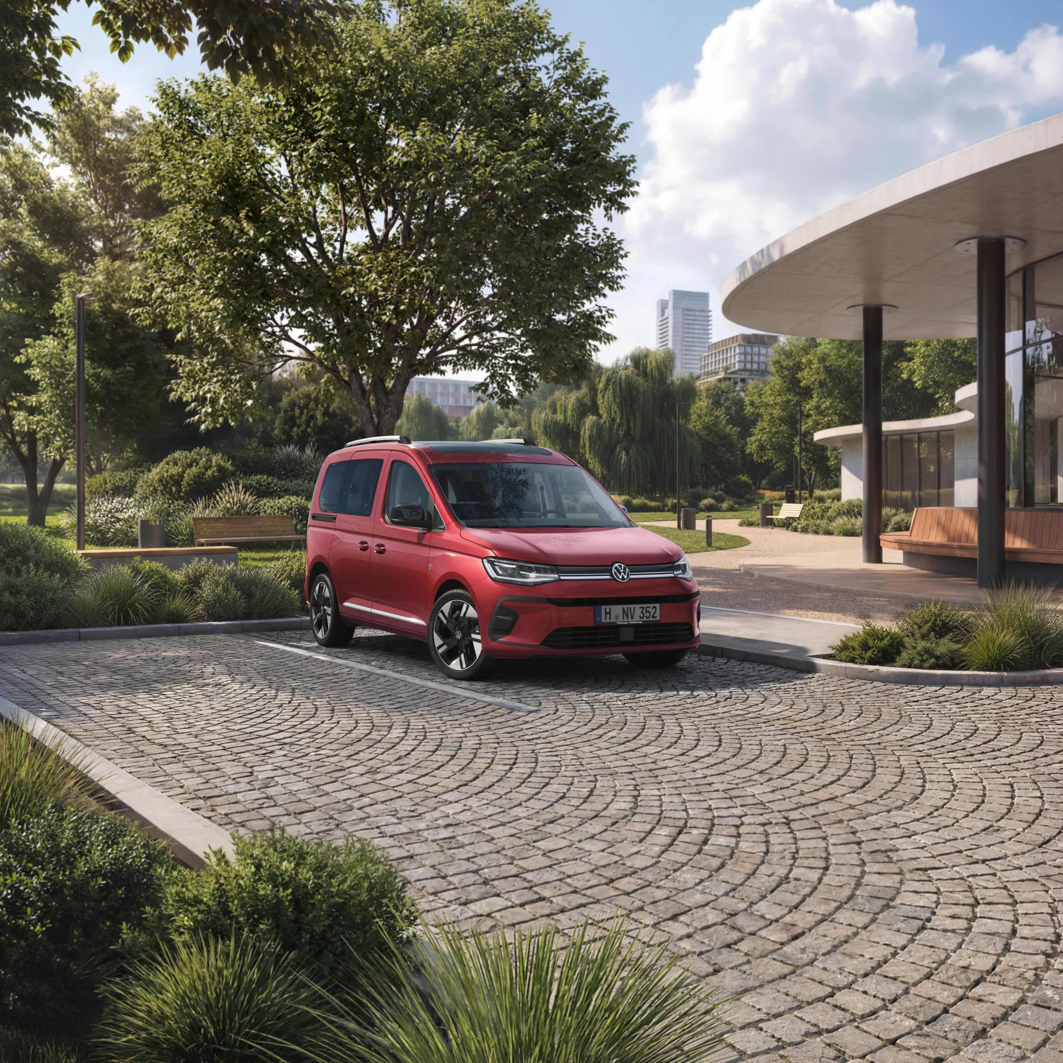 VW Caddy vermelha num estacionamento em frente a um parque numa cidade.
