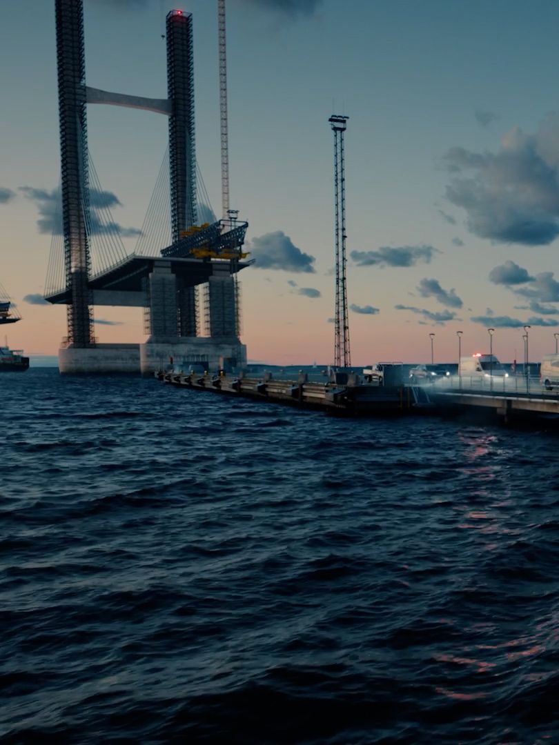 Uma série de veículos comerciais Volkswagen a caminho de casa, vindos de um estaleiro de construção numa ponte.