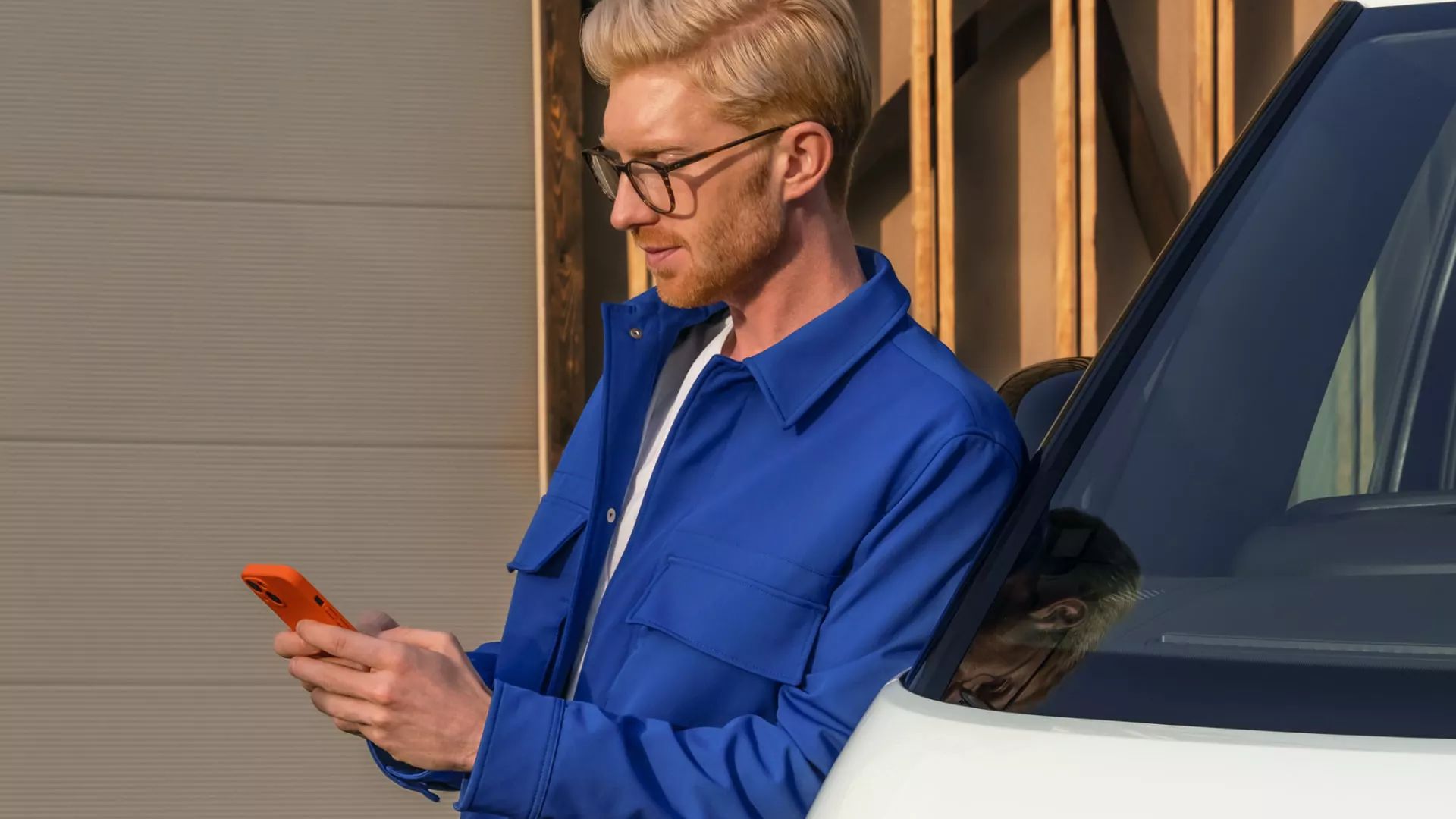 Mann lehnt an ID. Buzz Cargo und verwendet sein Smartphone