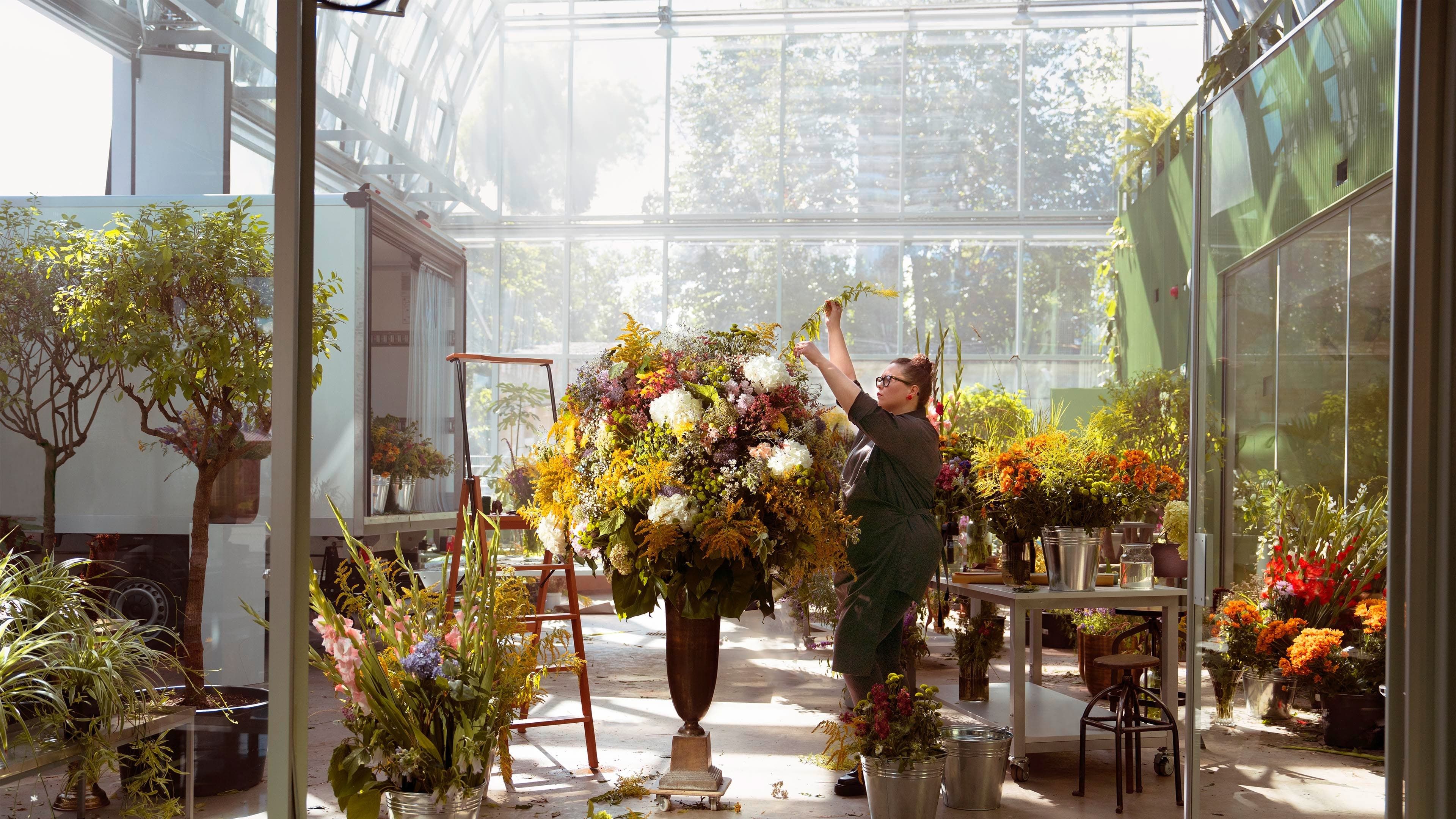 Uma florista compõe um enorme ramo de flores.
