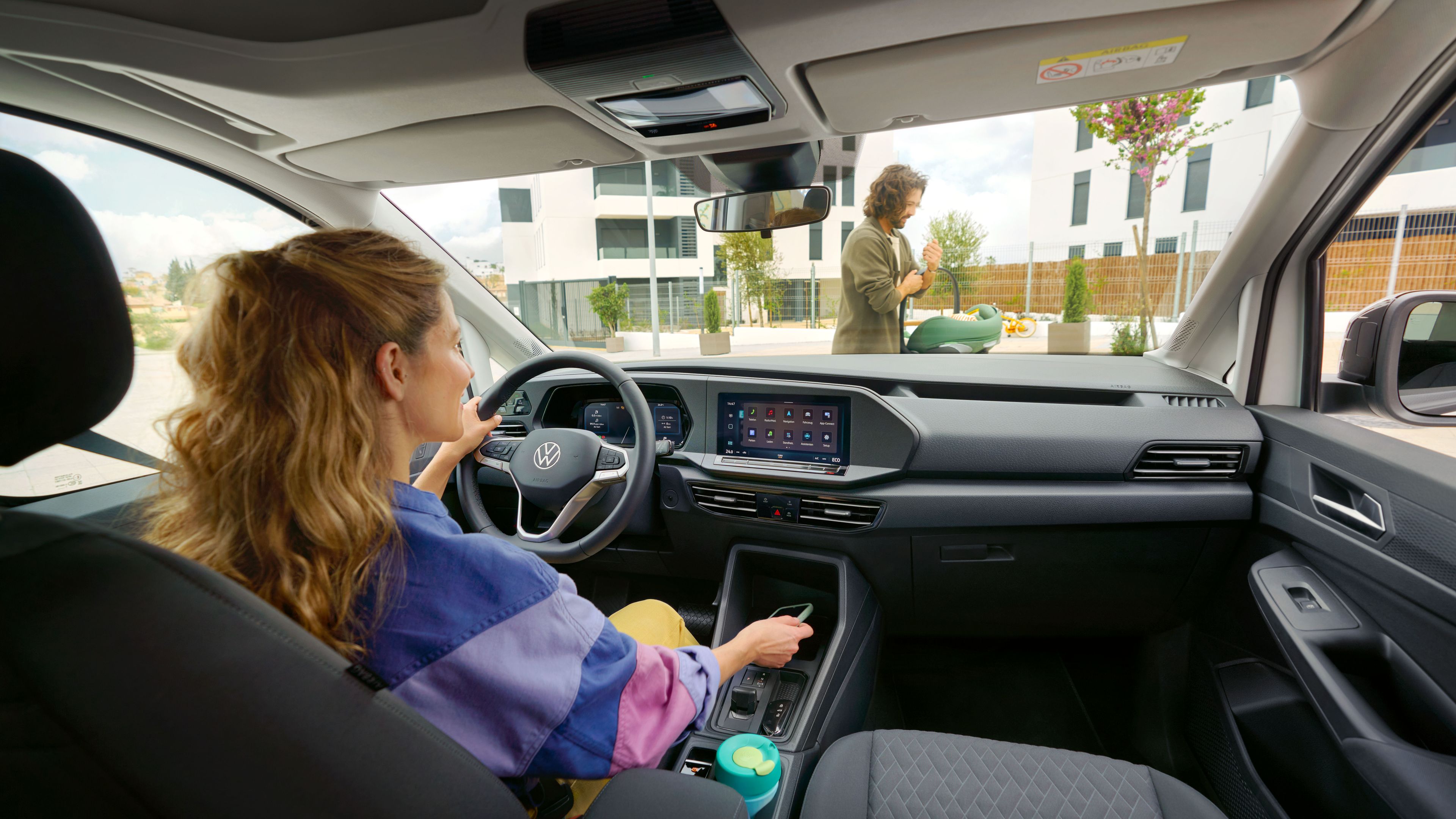 Uma pessoa está sentada no banco do condutor com uma mão no volante.