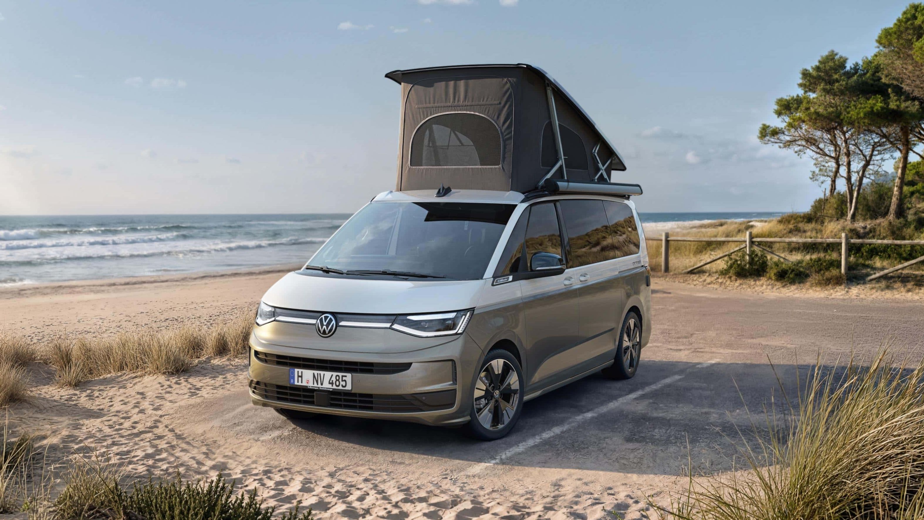 VW California com teto elevatório parada num estacionamento na praia.