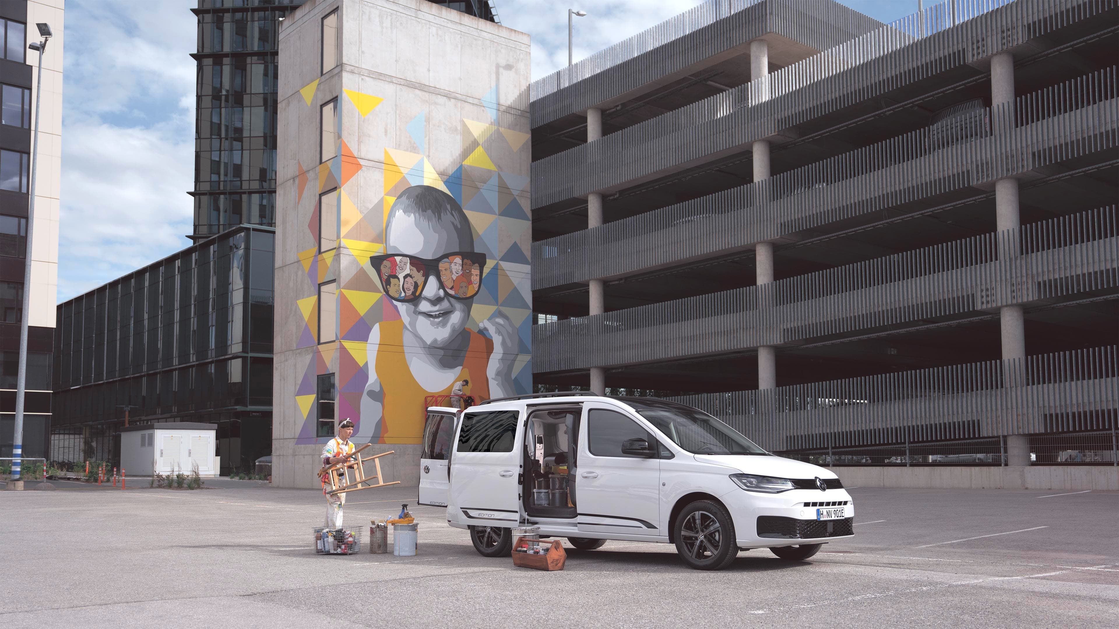 Uma mulher a transportar artigos de trabalho no Volkswagen Caddy. 