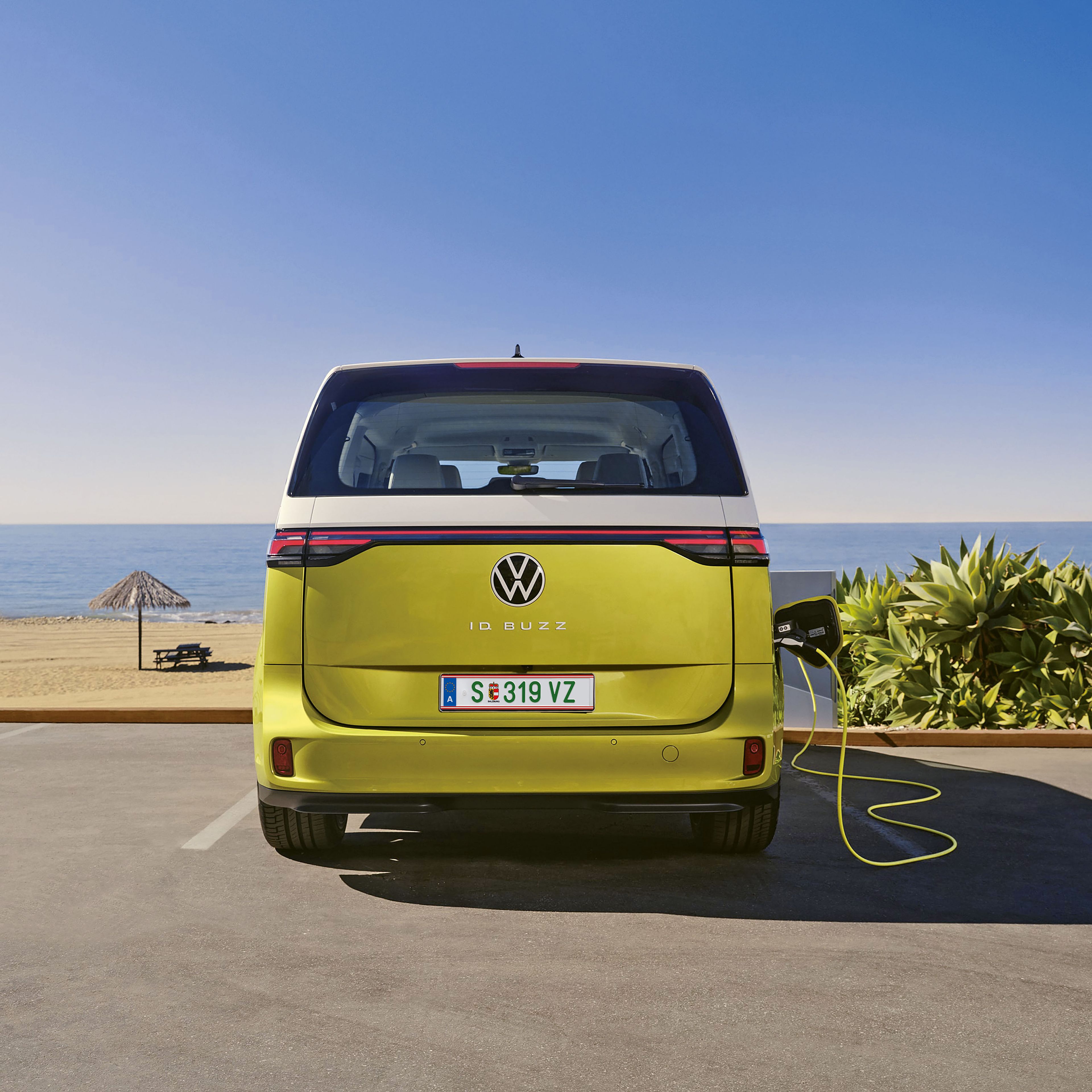 O ID. Buzz estacionado na praia junto a uma estação de carregamento.