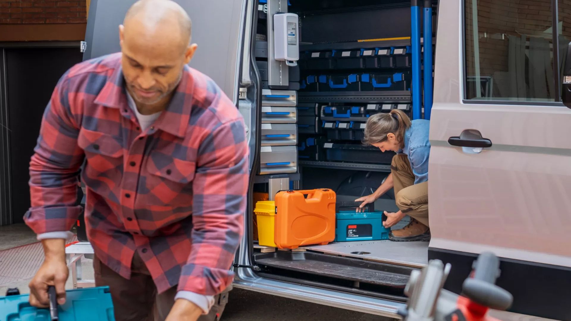 Zwei Handwerker nutzen einen VW Crafter als Arbeitsfahrzeug, geöffnete Schiebetür