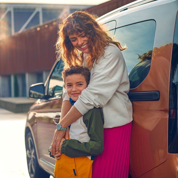 Eine Mutter steht mit ihrem Kind vor einem VW Nutzfahrzeug