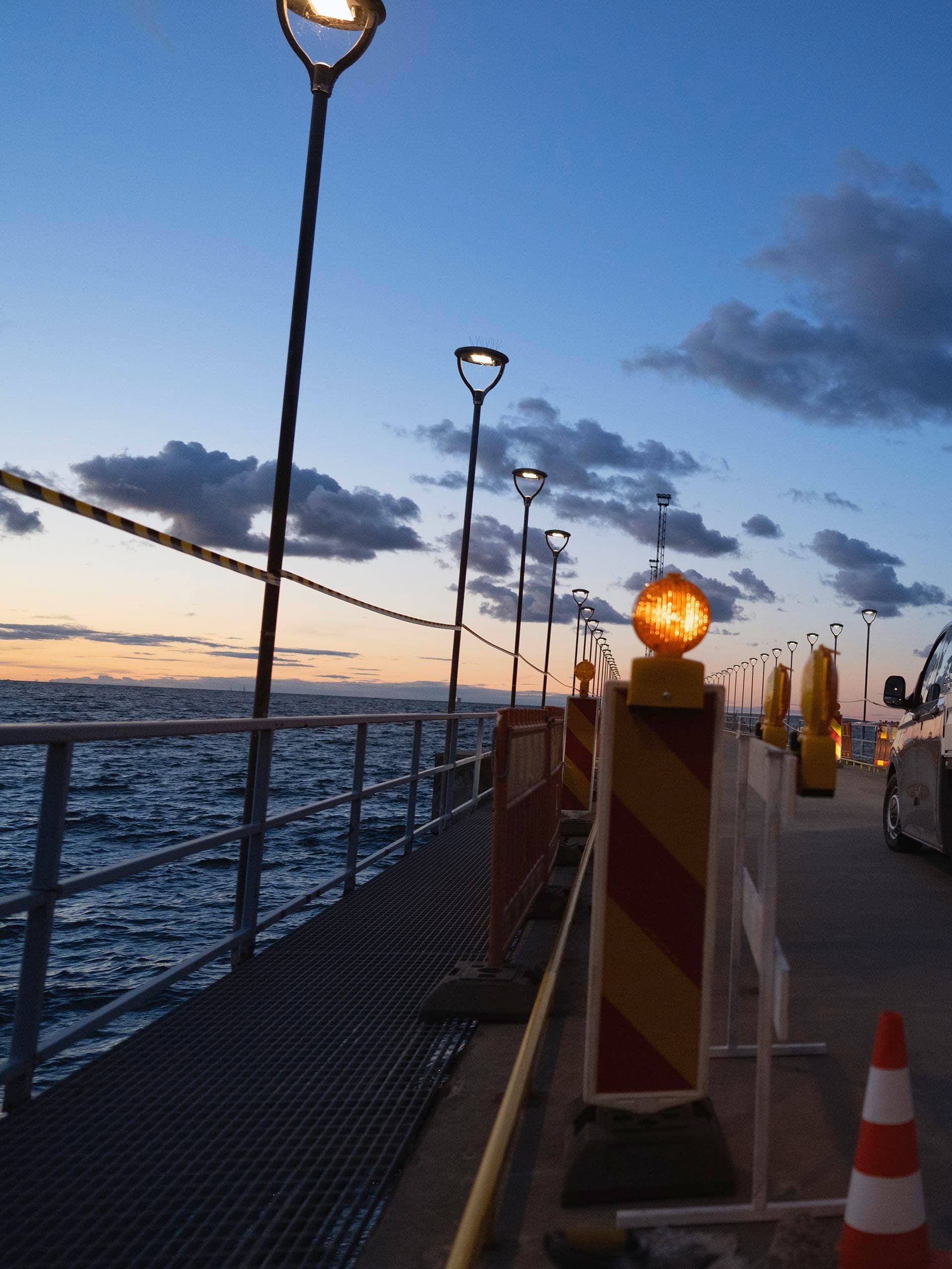 Um Volkswagen Crafter com plataforma de carga estacionada num estaleiro junto à água.