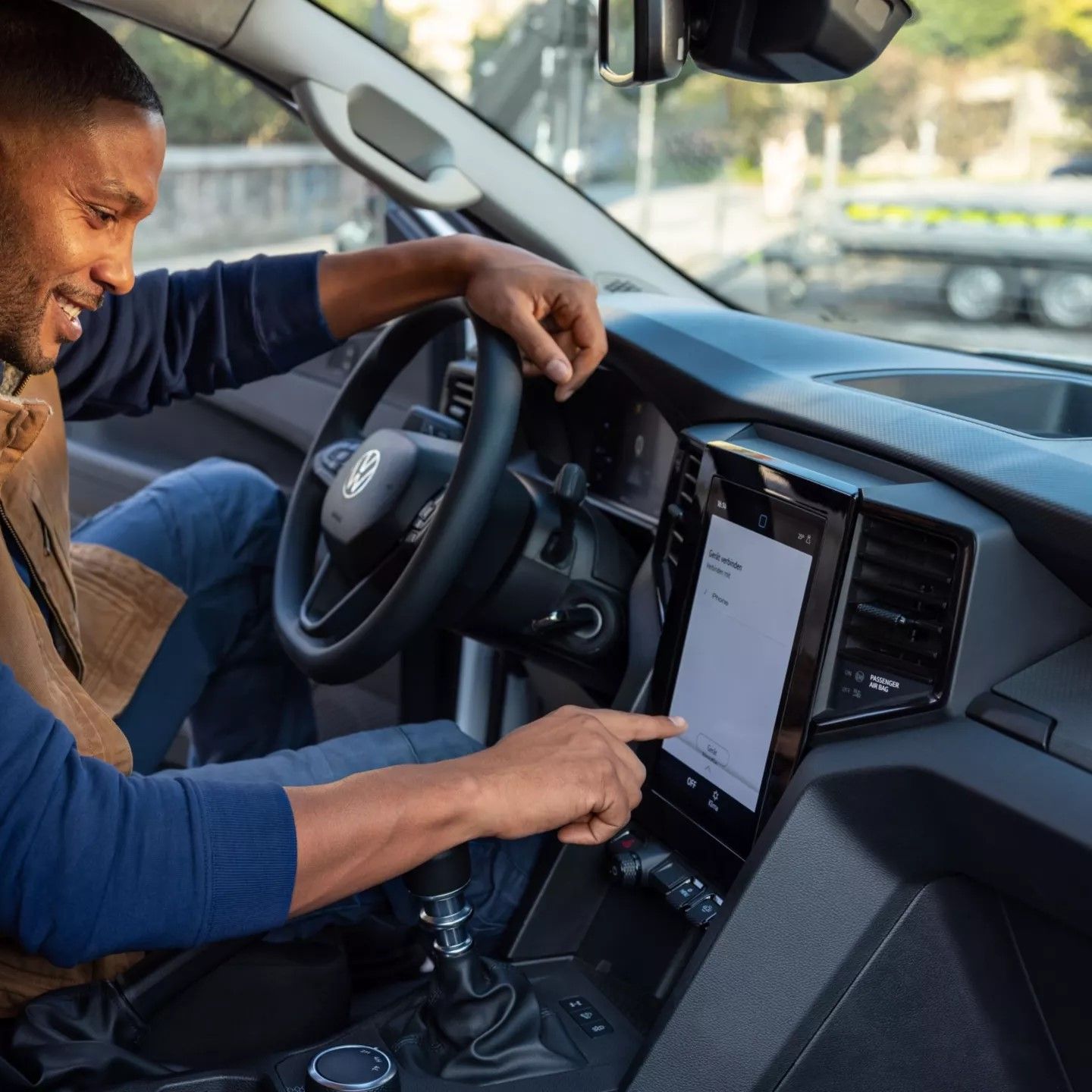 Um homem sentado no banco do condutor de um Amarok a utilizar a consola central.