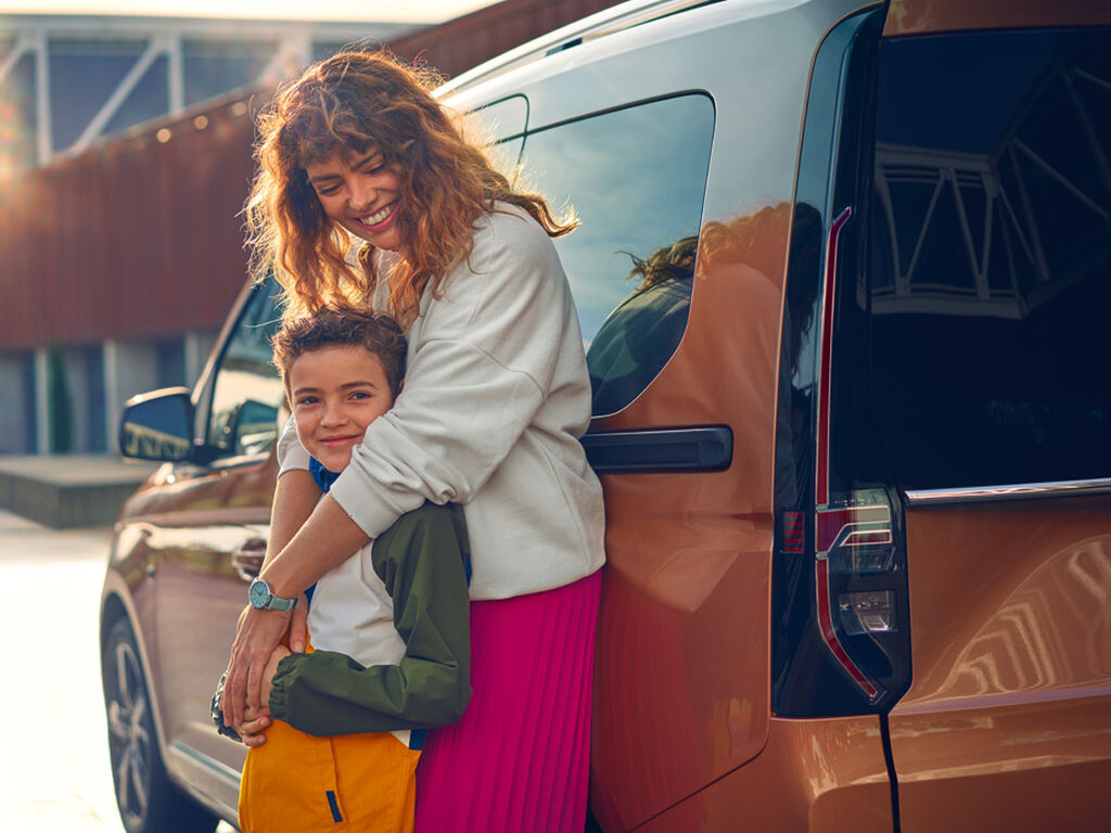 Eine Mutter steht mit ihrem Kind vor einem VW Nutzfahrzeug