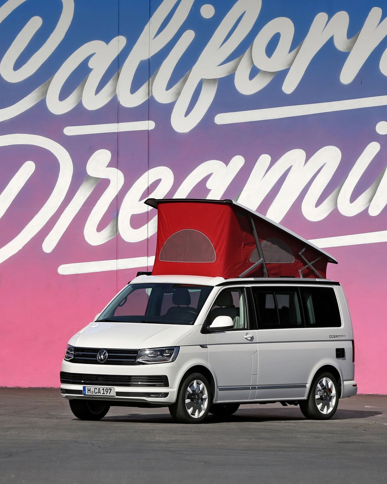 Uma Volkswagen California com telhado elevado está à frente da inscrição ilustrada "California Dreaming".