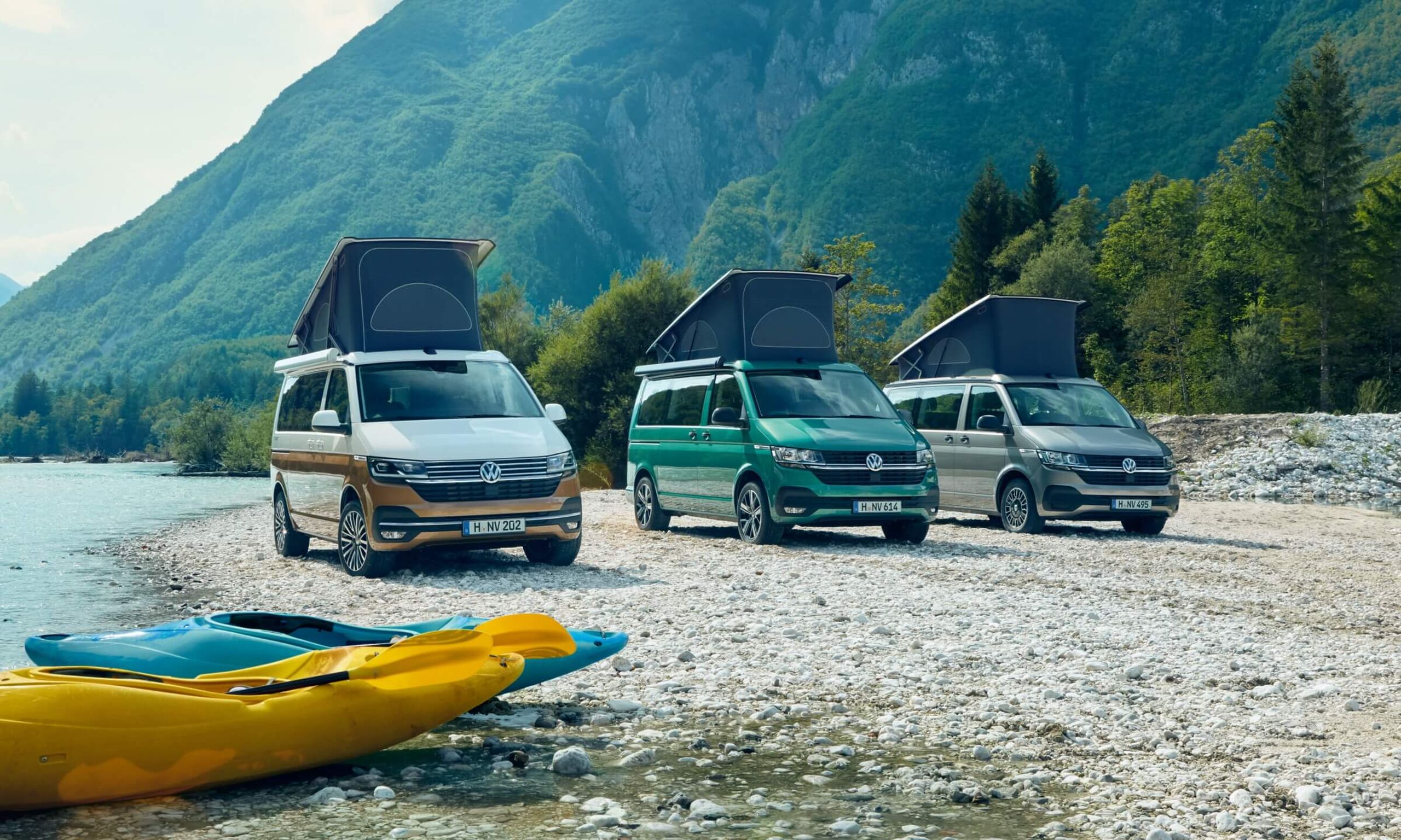 Três autocaravanas VW Californias 6.1 estacionadas num cenário de montanha ao pé de um lago.