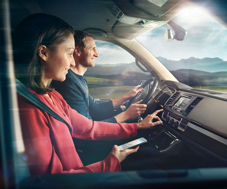 Um homem e uma mulher no cockpit de uma carrinha comercial Volkswagen.