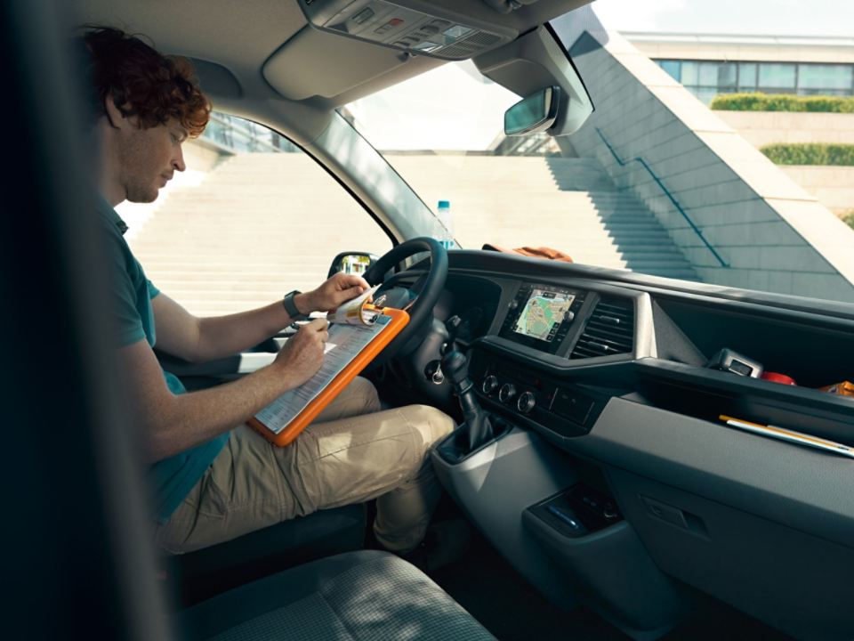 Um homem sentado a escrever no lugar do condutor da Transporter 6.1.