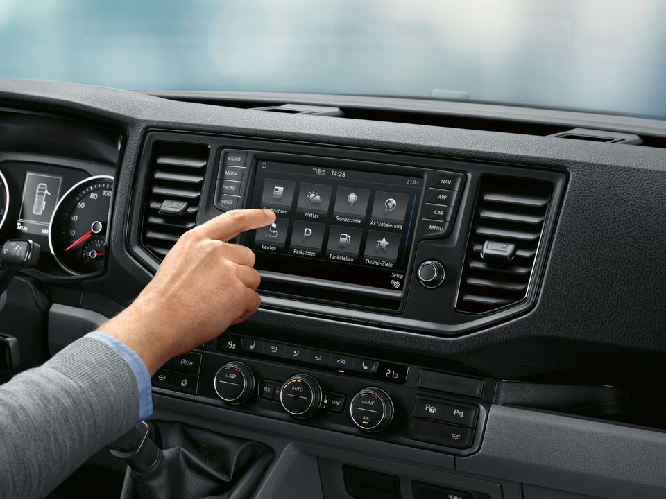 Na cabina do condutor da VW Crafter parada. No fundo pode ver-se o serviço online Car-Net no ecrã multifunções.