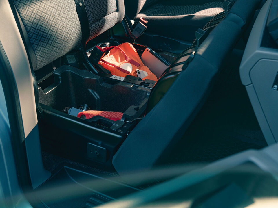 Caixas de arrumação por baixo do duplo assento na kombi Volkswagen Caravelle.