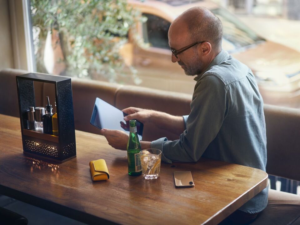 Homem com tablet sentado à mesa com a nova carrinha Caddy em segundo plano