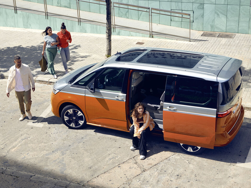 Jovens em volta de um VW Multivan Energetic estacionado.