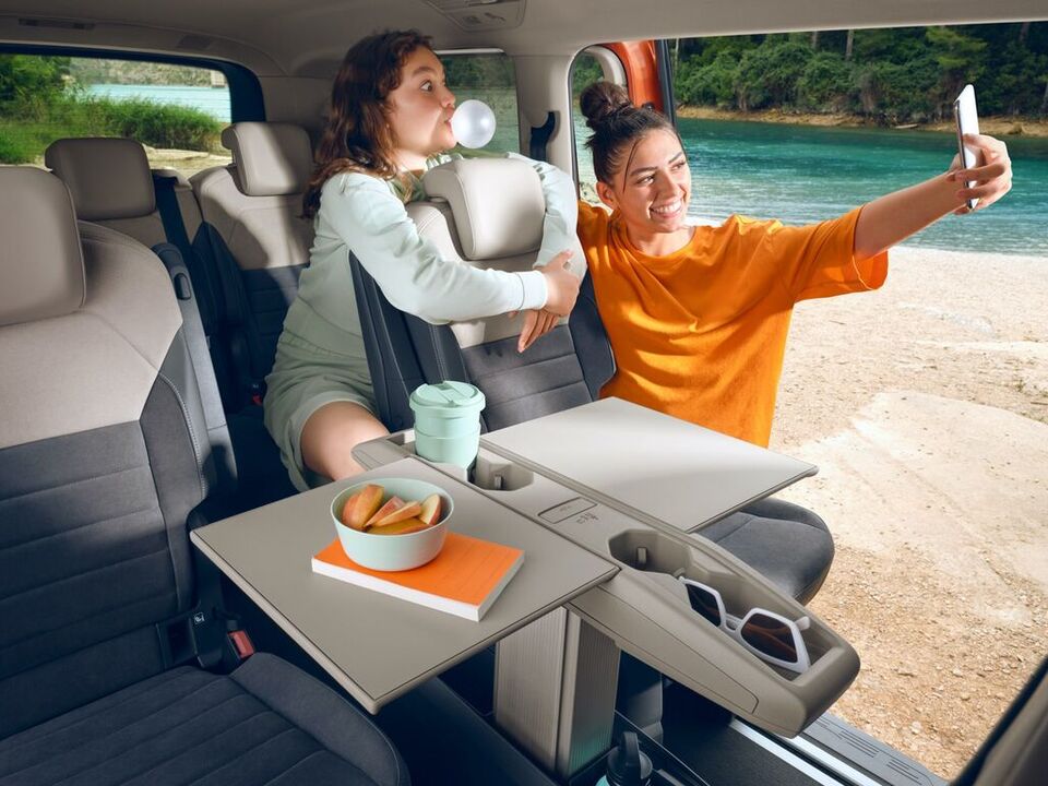 Duas mulheres tiram fotografias no Multivan da Volkswagen com a mesa multifunções dobrada.