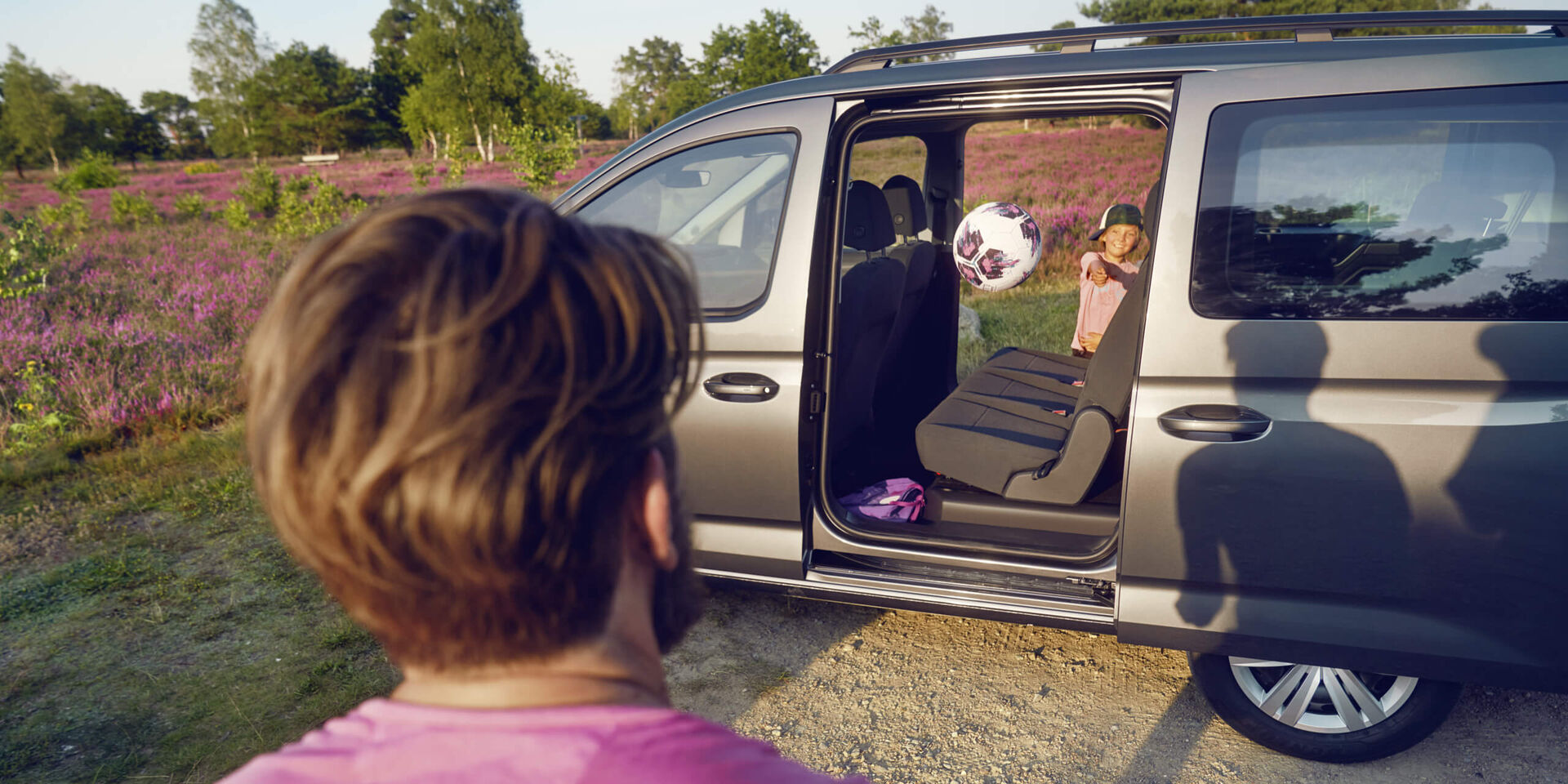 Criança lança a bola pelo interior do VW Caddy Maxi com as portas deslizantes abertas