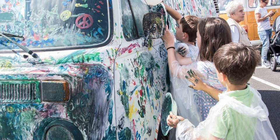No Festival de Verão Pão de Forma 2017, as crianças pintam com os dedos e tintas coloridas uma carrinha Pão de Forma branca