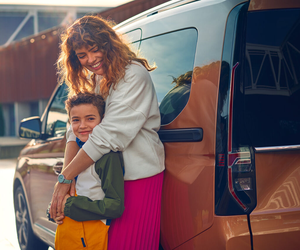 Eine Mutter steht mit ihrem Kind vor einem VW Nutzfahrzeug