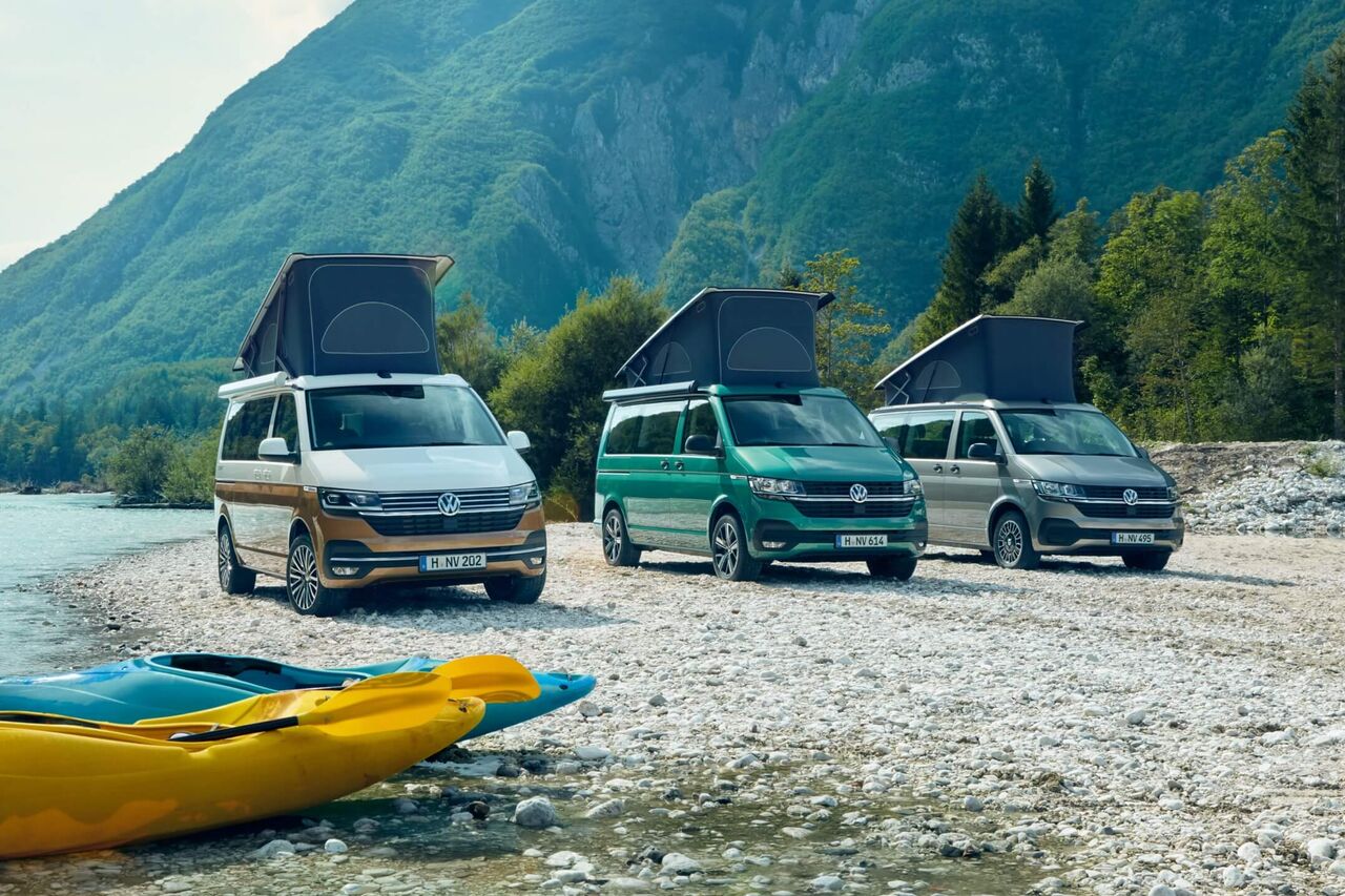 Três autocaravanas VW Californias 6.1 estacionadas num cenário de montanha ao pé de um lago.