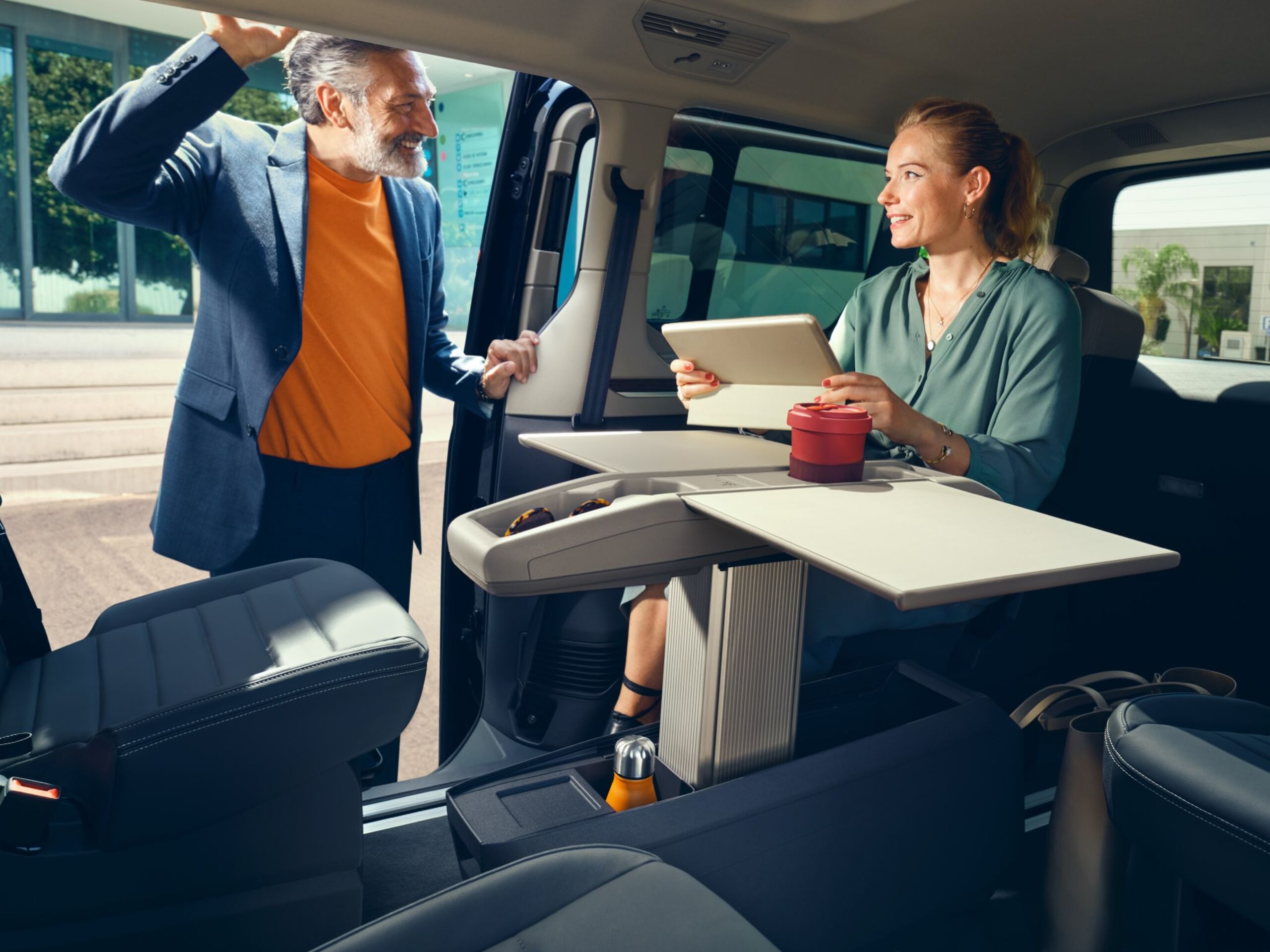 Eine Frau und ein Mann unterhalten sich am Multifunktionstisch im neuen VW Multivan T7 2021.