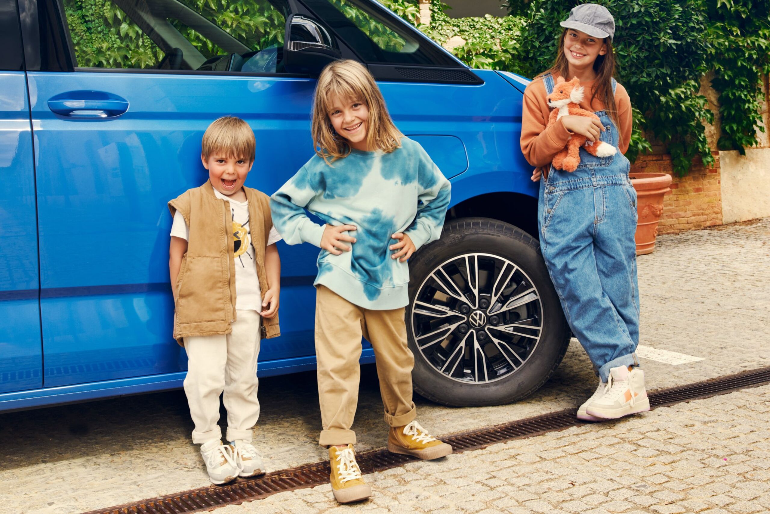 Três crianças ao lado da Multivan da Volkswagen.