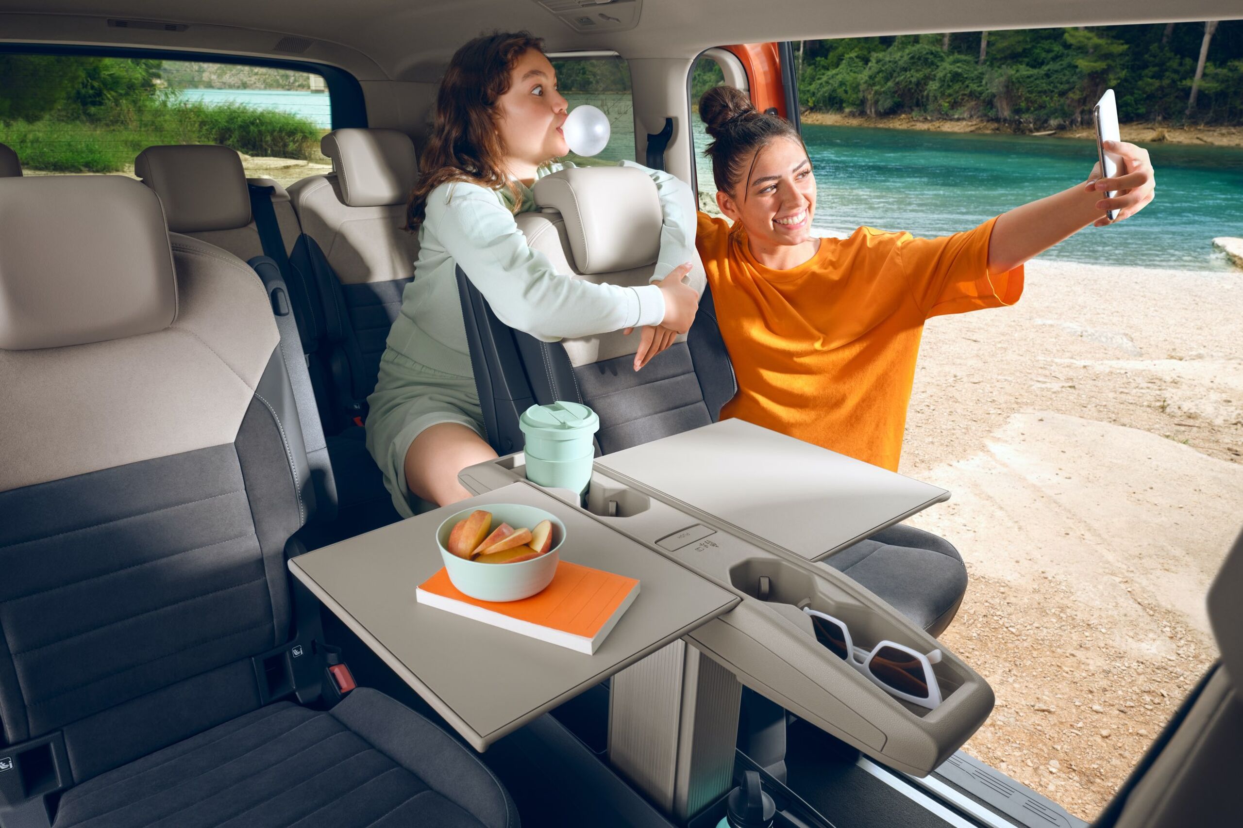 Duas mulheres tiram fotografias no Multivan da Volkswagen com a mesa multifunções dobrada.