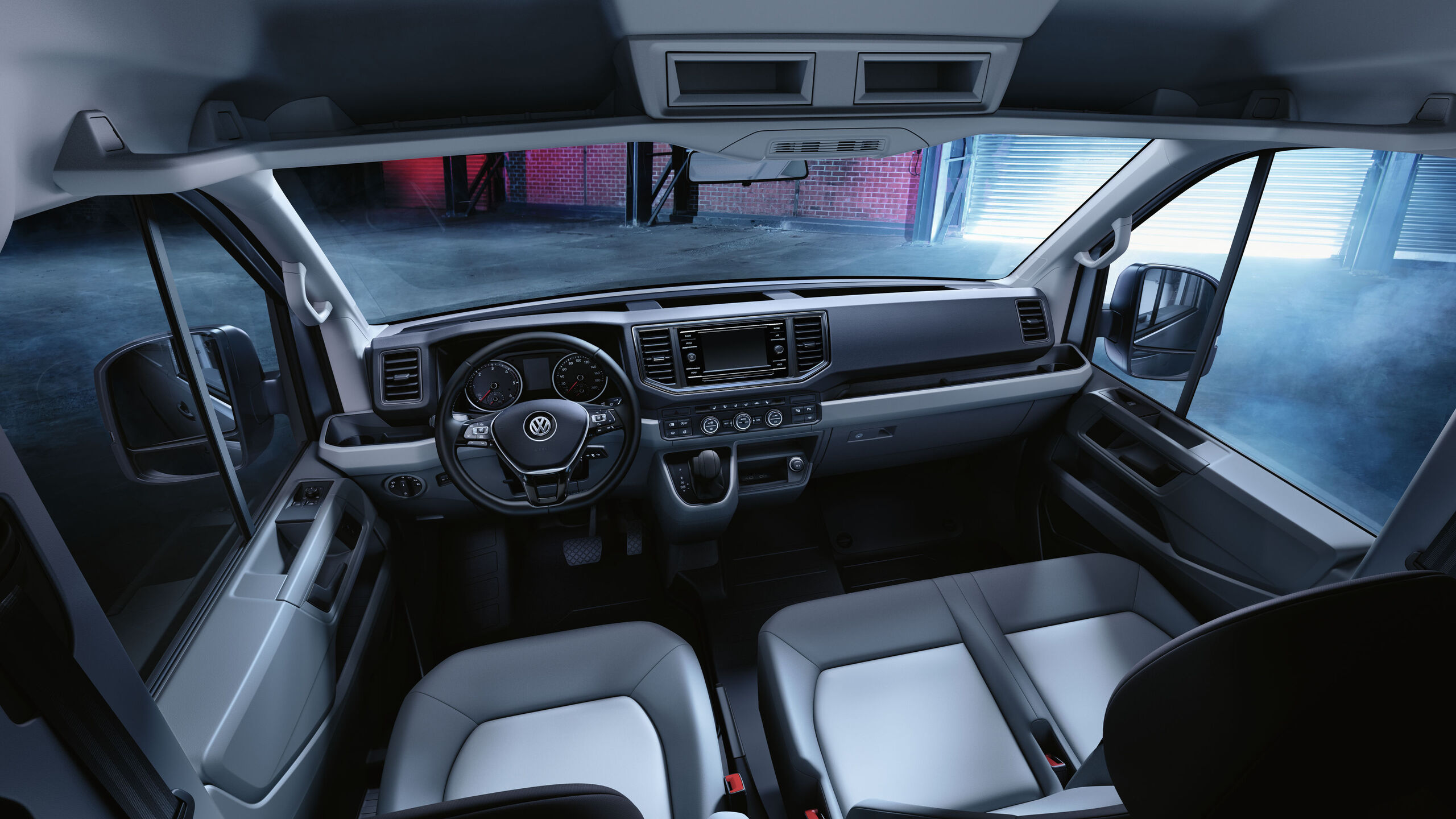 Uma visão da cabina do condutor do VW Crafter com inúmeras arrumações e compartimentos.