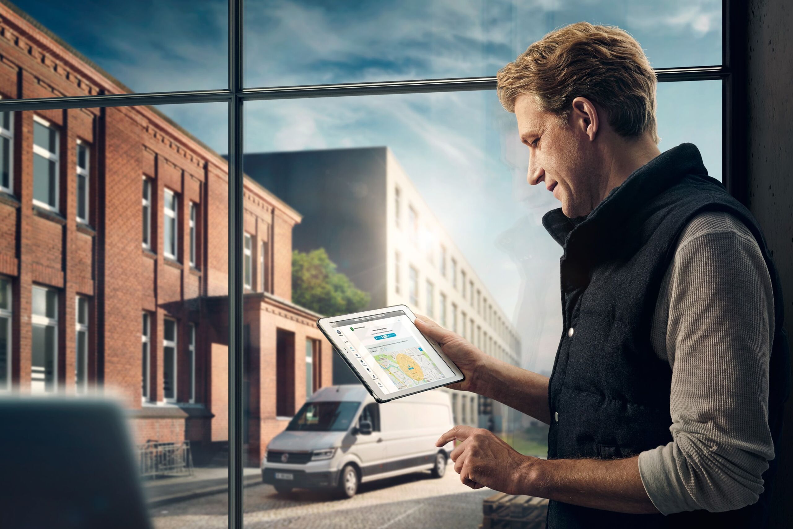 Um homem utiliza o Car-Net num tablet. Do lado de fora está estacionada uma carrinha Volkswagen.