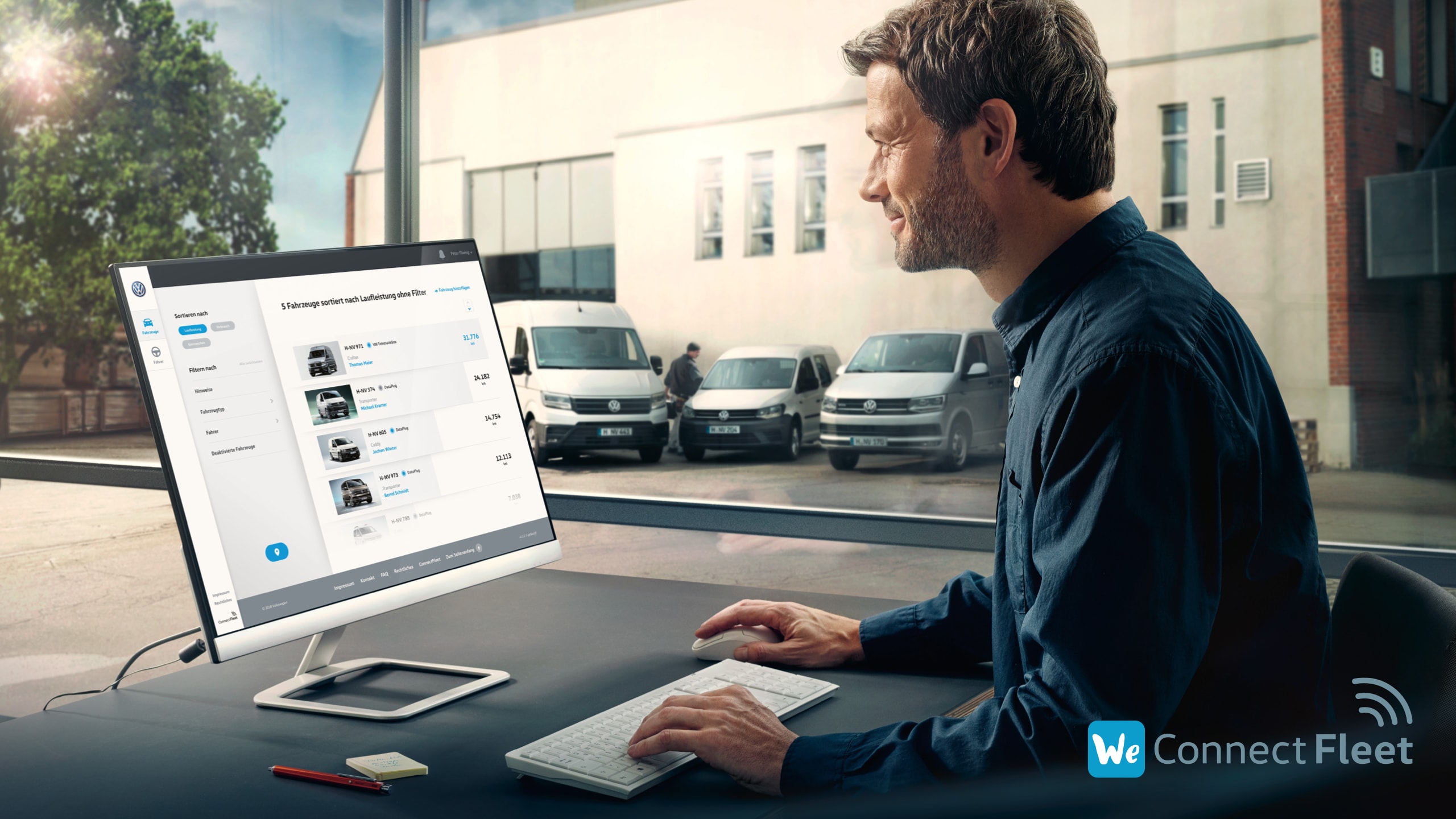 Um homem está sentado no escritório com um computador à frente. No ecrã pode ver-se o sistema de gestão de frotas We Connect Fleet da Volkswagen. Através da janela, pode ver-se o estacionamento da empresa com três carrinhas da Volkswagen Veículos Comerciais.