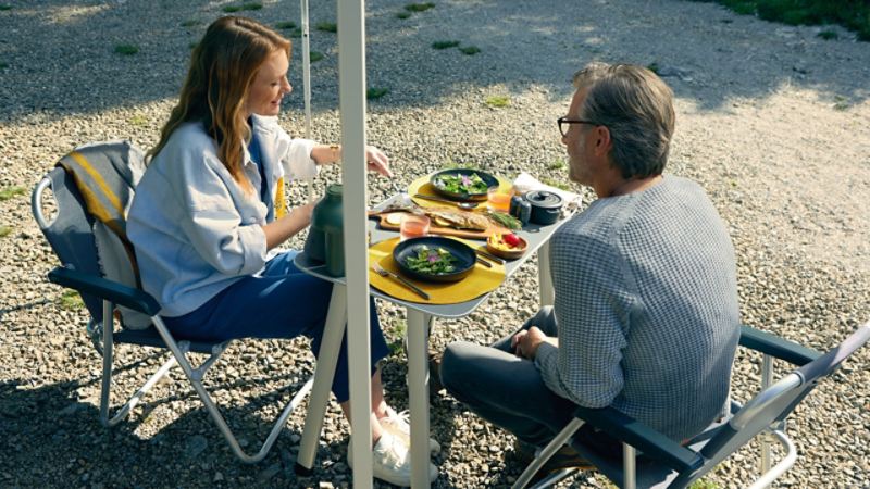 Um casal desfruta de uma refeição numa mesa de campismo 